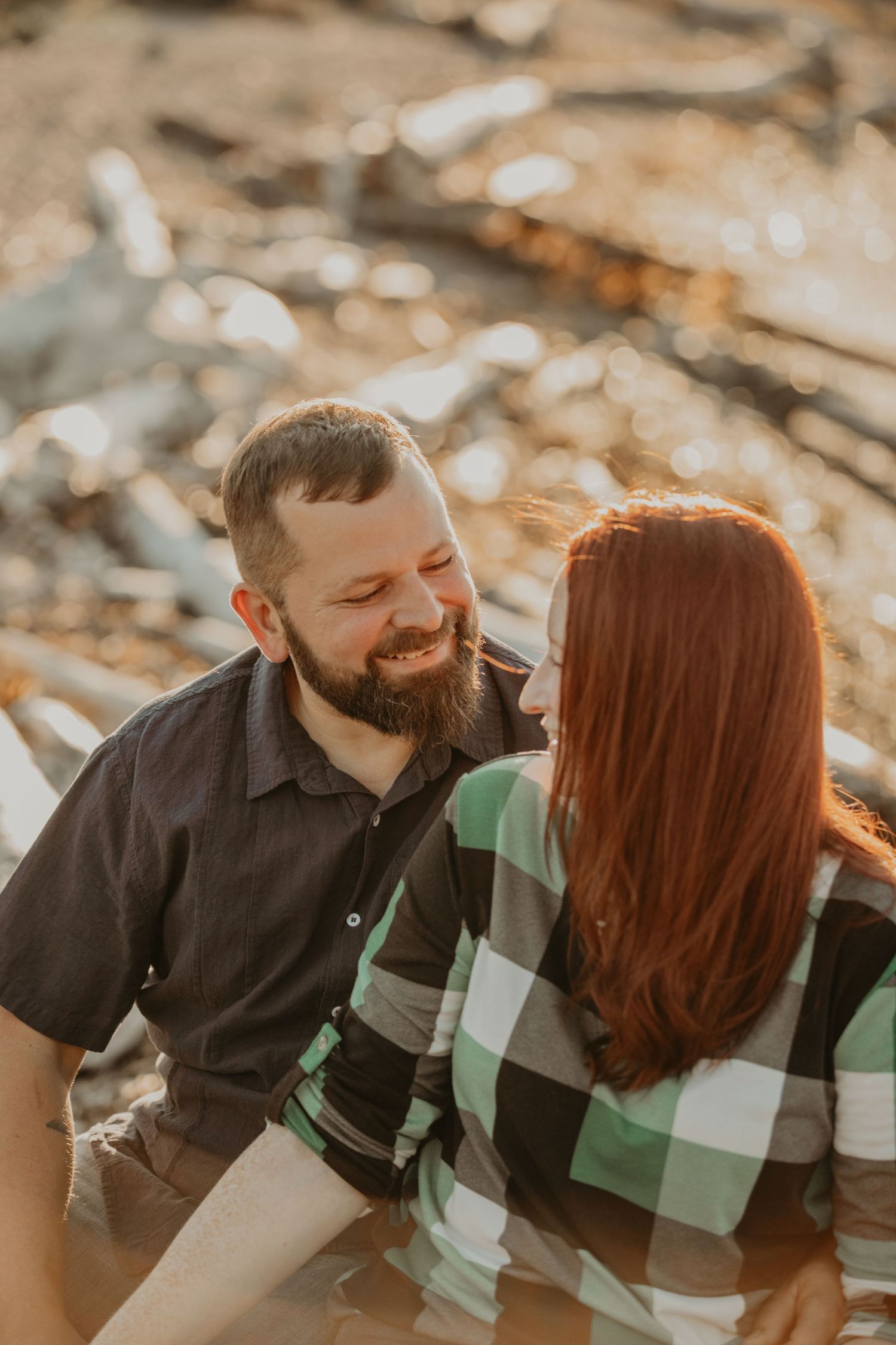A couple sharing an intimate romantic moment at sunset wearing a checkered shirt and dark top.
