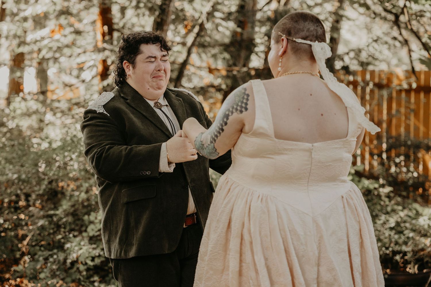 A couple shares an intimate dance moment during their wedding celebration in a golden-lit outdoor setting.
