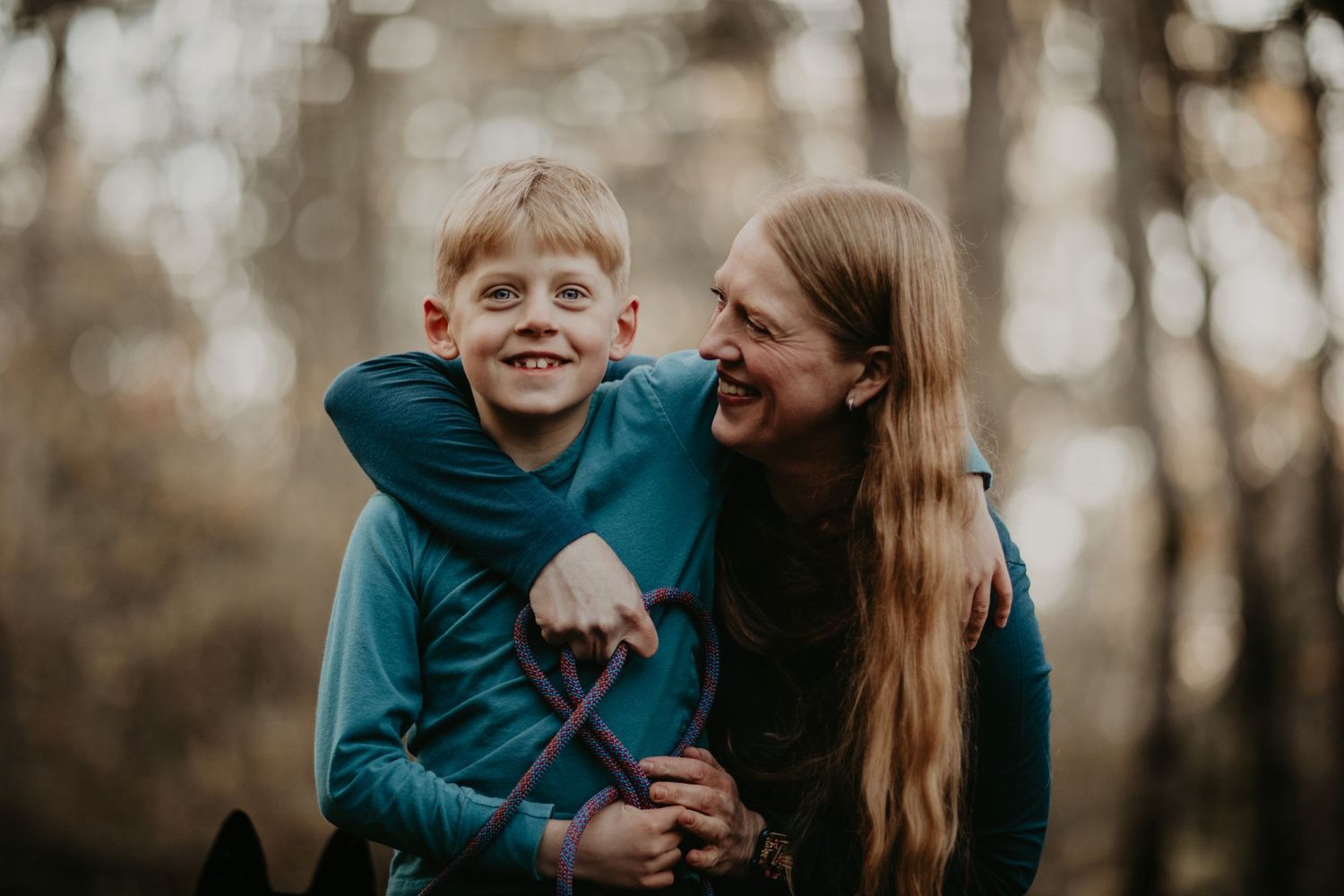 Two people share a joyful moment together while hugging and laughing in an autumn forest setting.