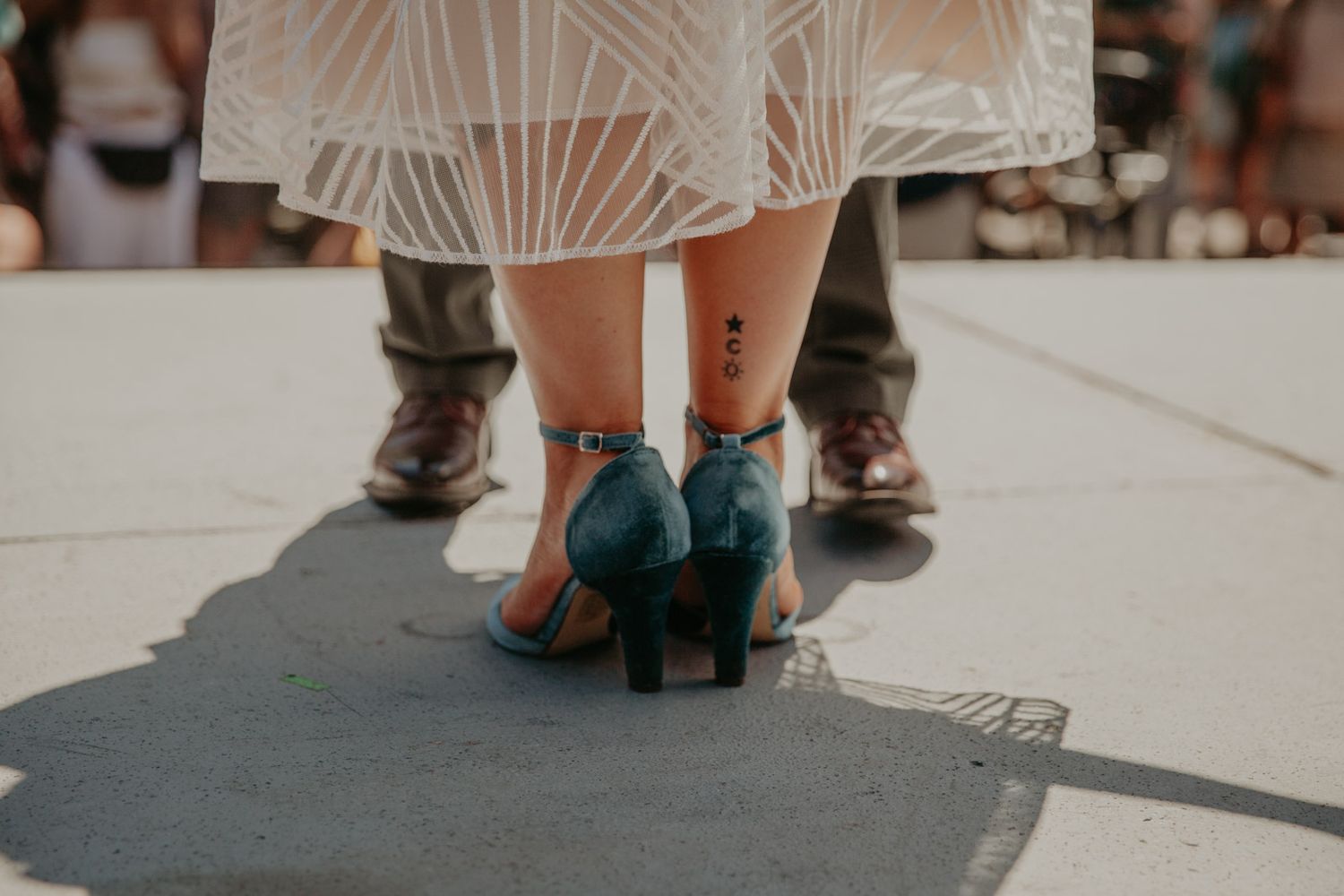 Feet of a wedding party standing together on a sidewalk showing dress shoes and formal attire details.