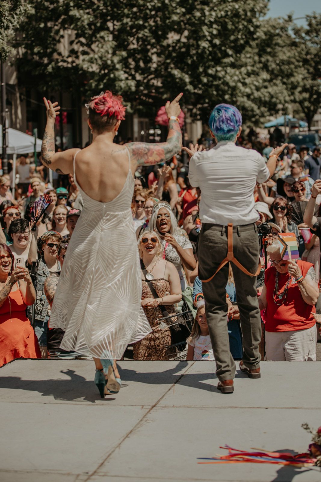 Energetic crowd gathers outdoors on a sunny day for a lively street performance or celebration.