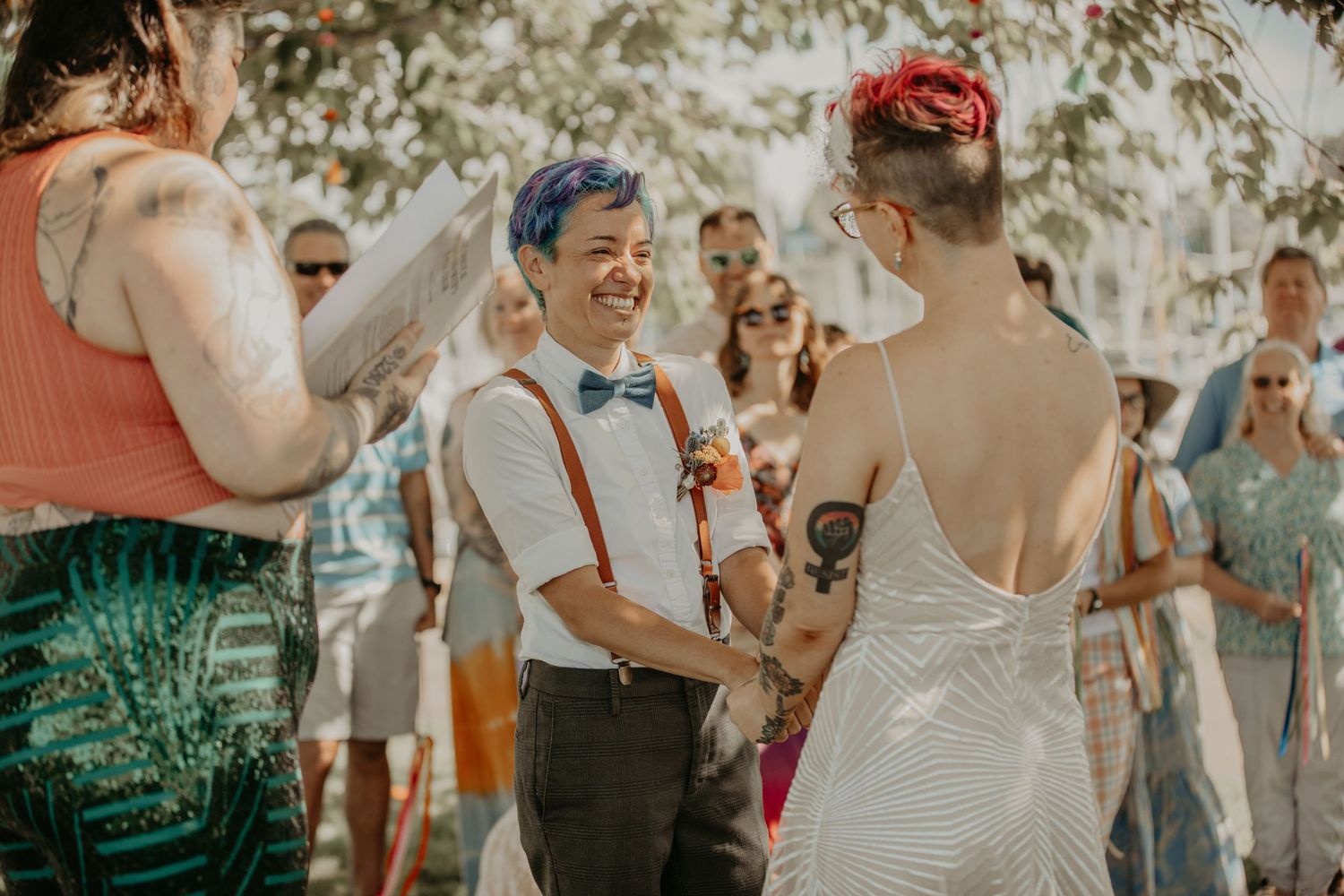Happy couple celebrates during outdoor wedding ceremony with guests clapping in background during golden hour.