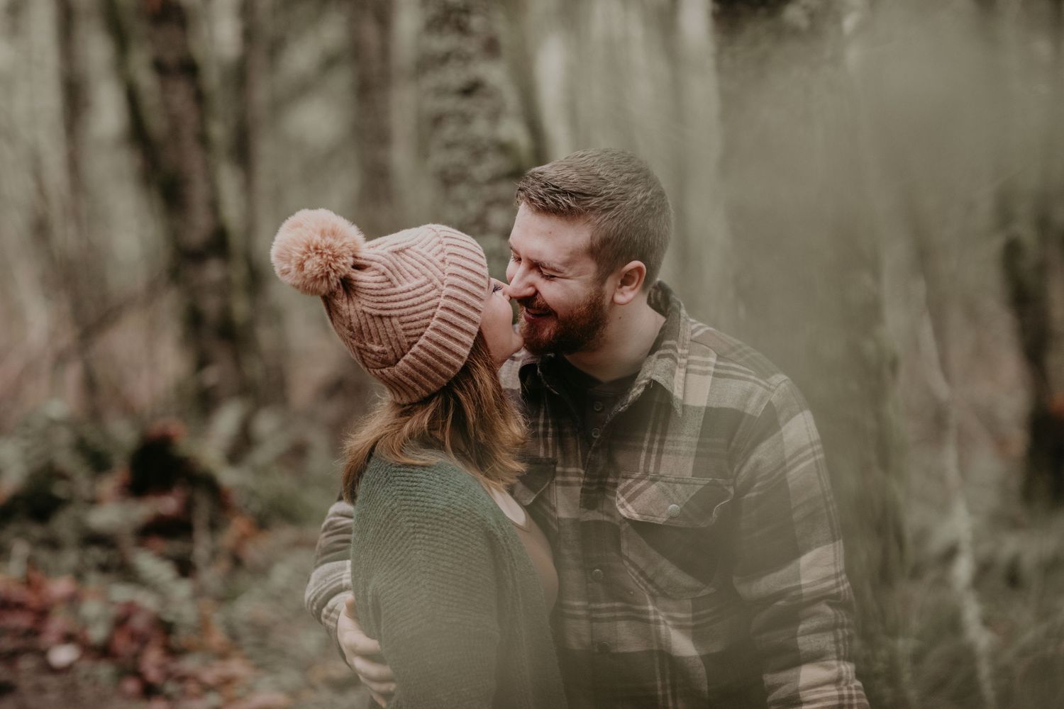 A romantic autumn moment captured in a misty forest setting with two people sharing an intimate embrace.