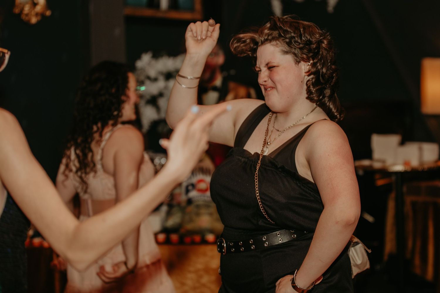 People dance and celebrate at an indoor party venue with warm lighting and festive atmosphere.