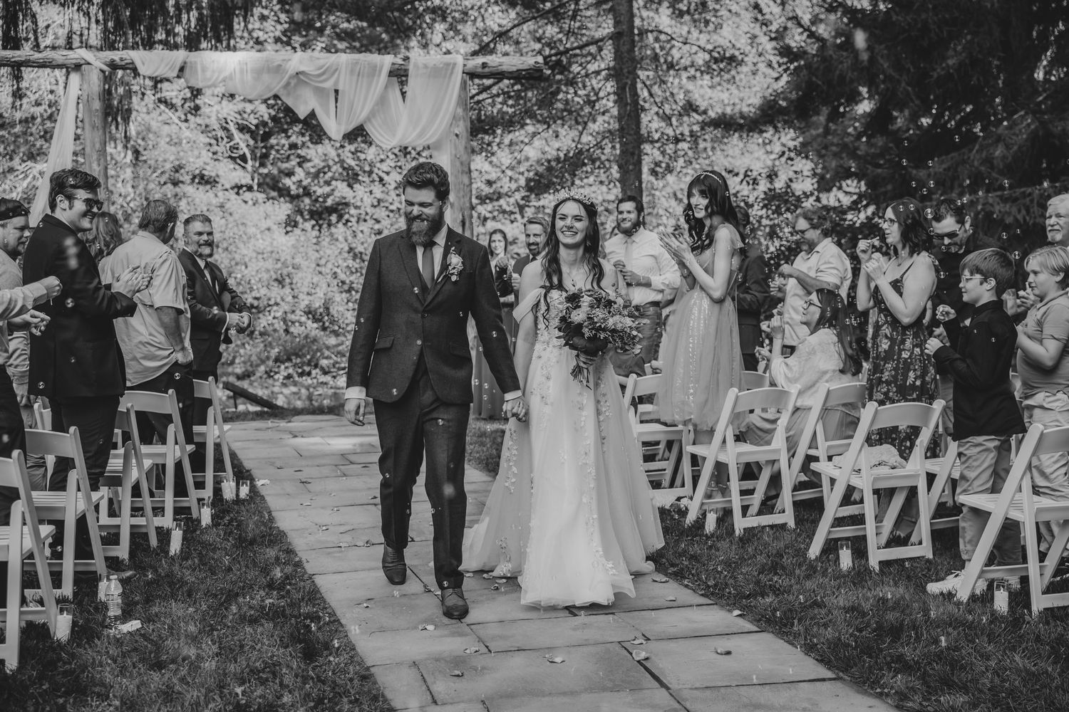 A black and white photo sequence shows a wedding ceremony processional along an outdoor garden path with chairs.