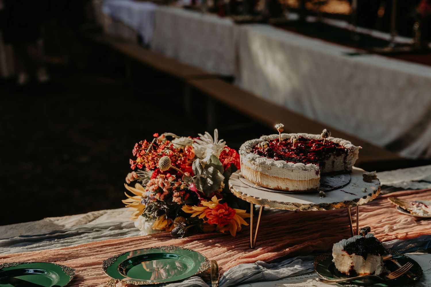 Rustic wooden table set with various desserts and cakes decorated with autumn flowers and greenery.