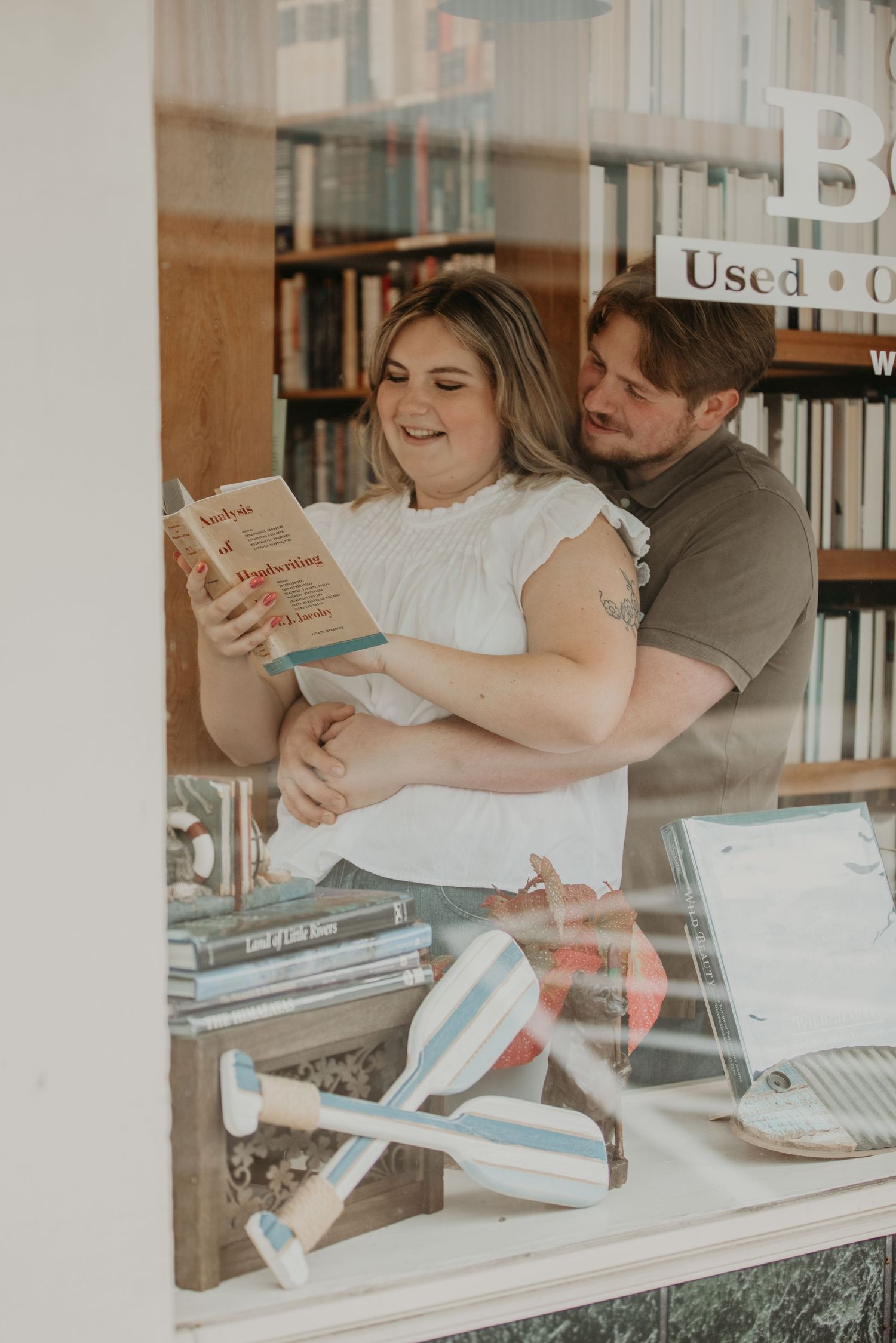 Two people browsing books together in a cozy used bookstore while sharing an intimate moment.