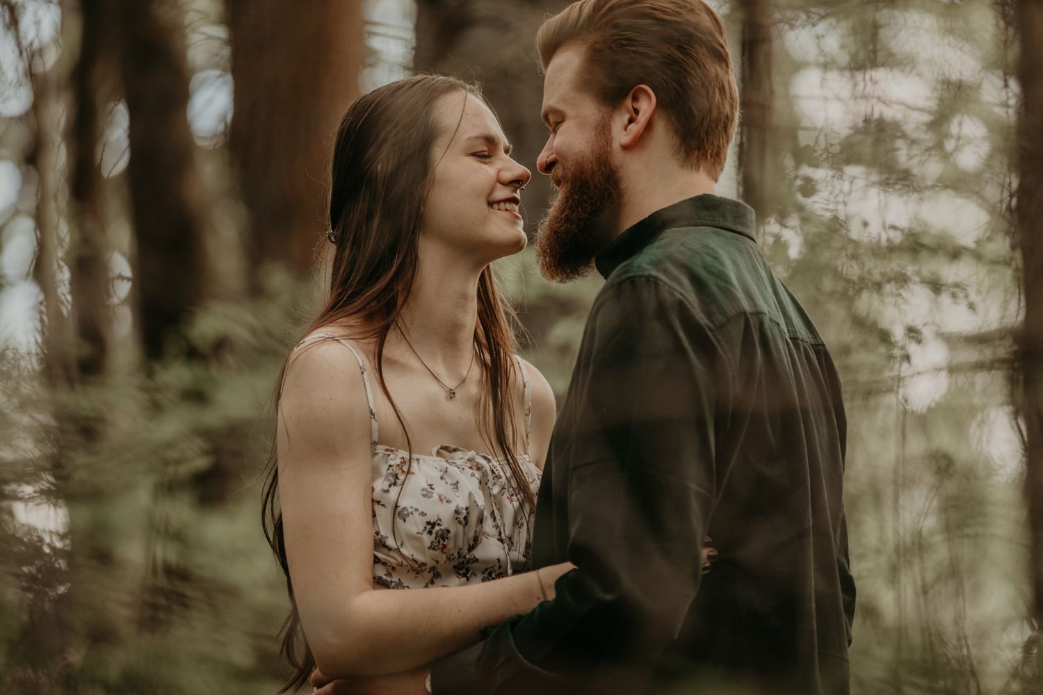 A romantic couple embraces in a sunlit forest setting during an intimate outdoor photo session.