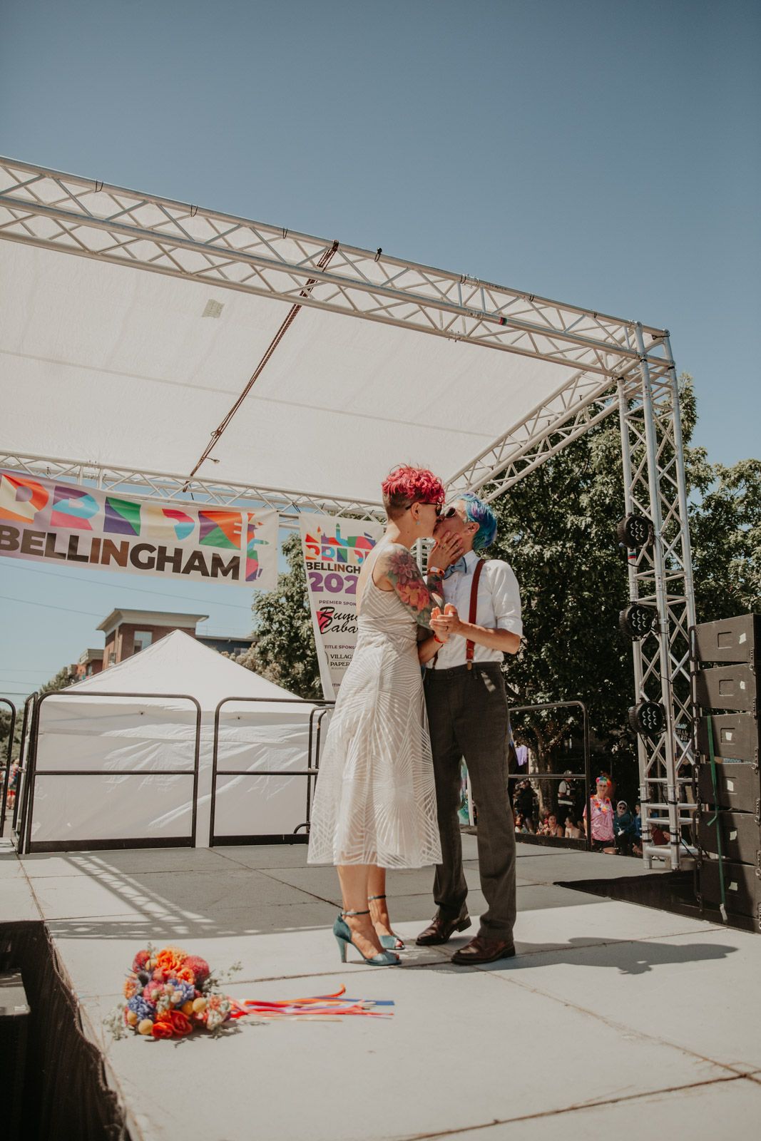 A couple shares a tender moment during their outdoor wedding ceremony under a white tent structure.