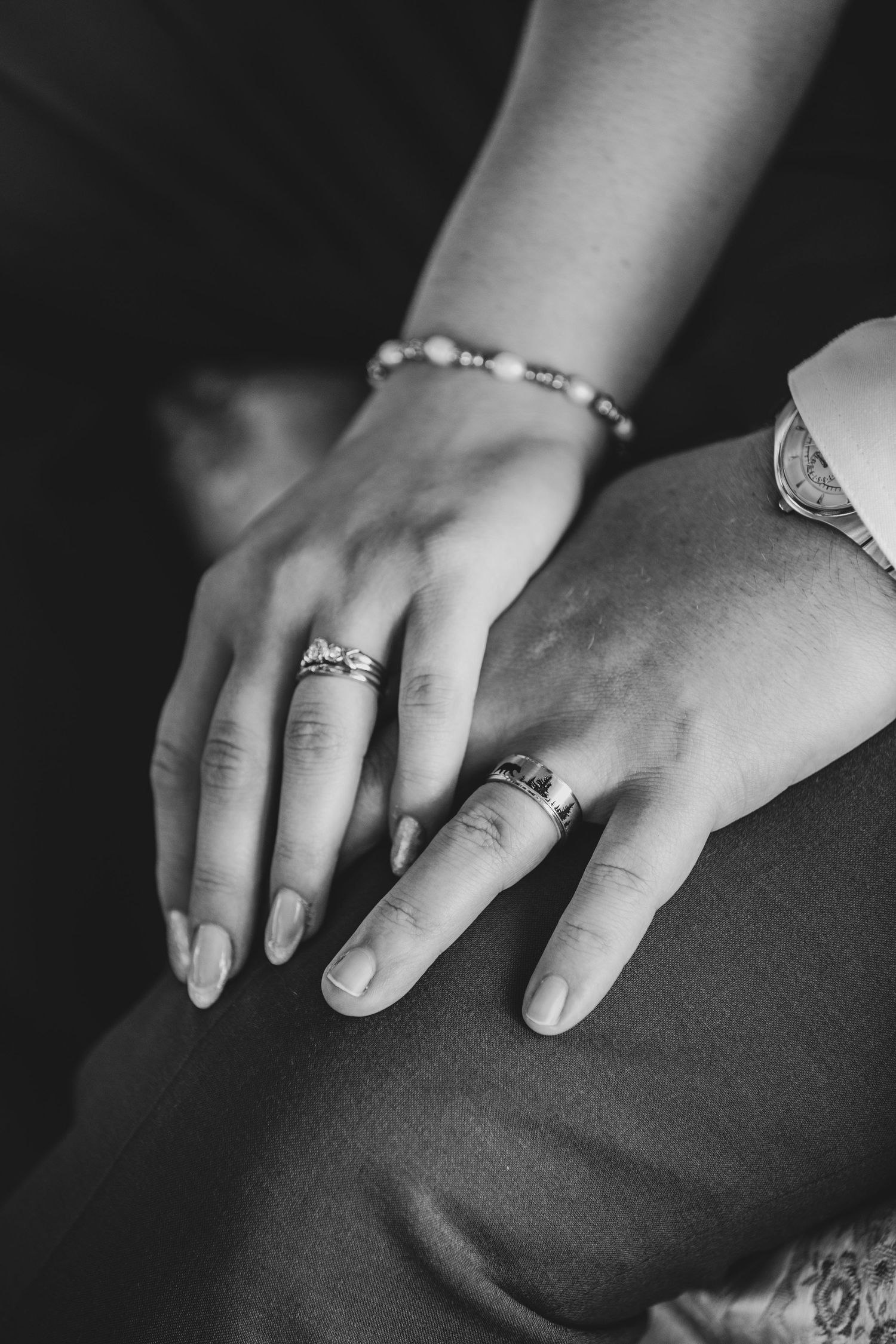 Close-up shot of hands wearing wedding rings and delicate jewelry.