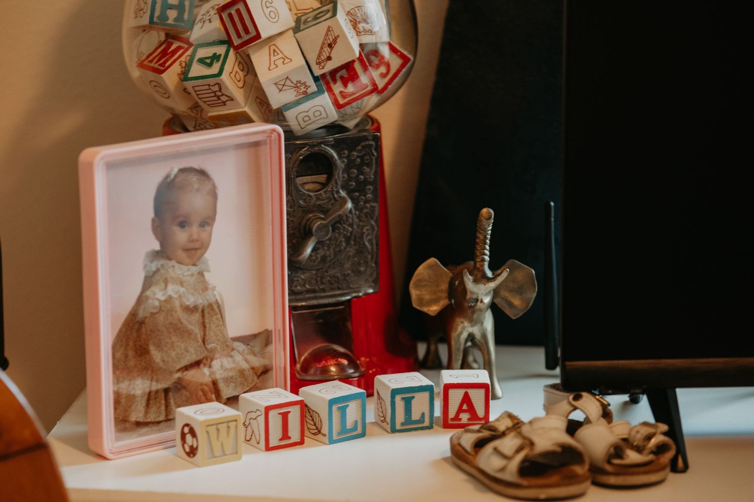 Vintage baby toys and decorative items including wooden blocks, sandals, and a stuffed mouse arranged on a surface.