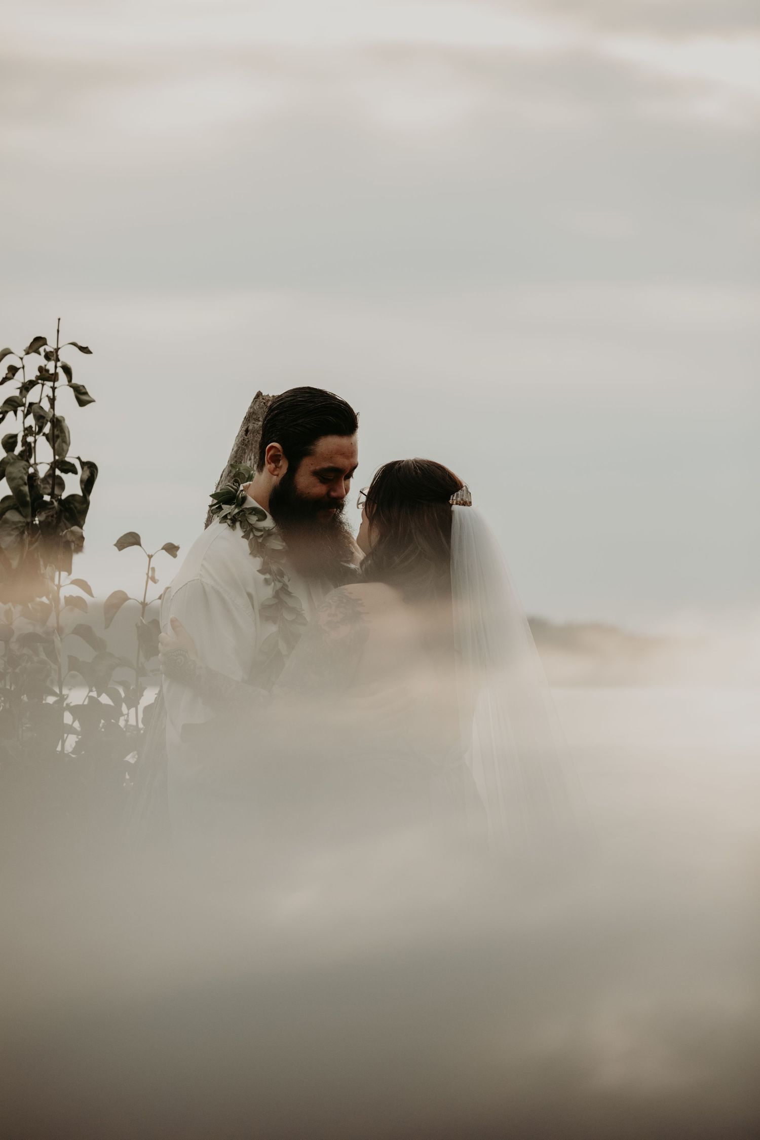 A dreamy misty outdoor portrait of a couple standing close together in soft natural lighting.