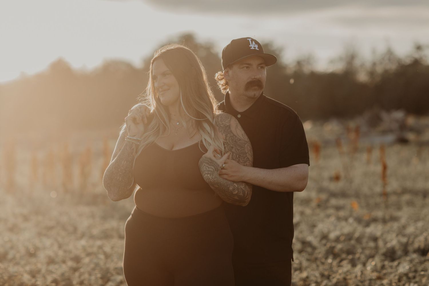 Couple laughing together in outdoor setting during warm sunset lighting.