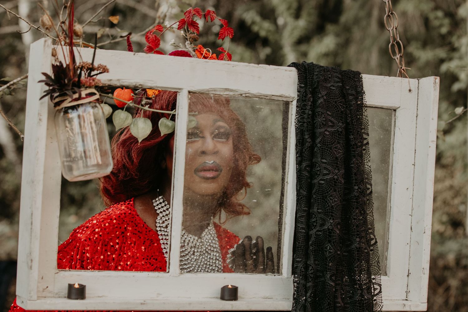 A vintage window frame displays artistic photos with red accents against a natural background.