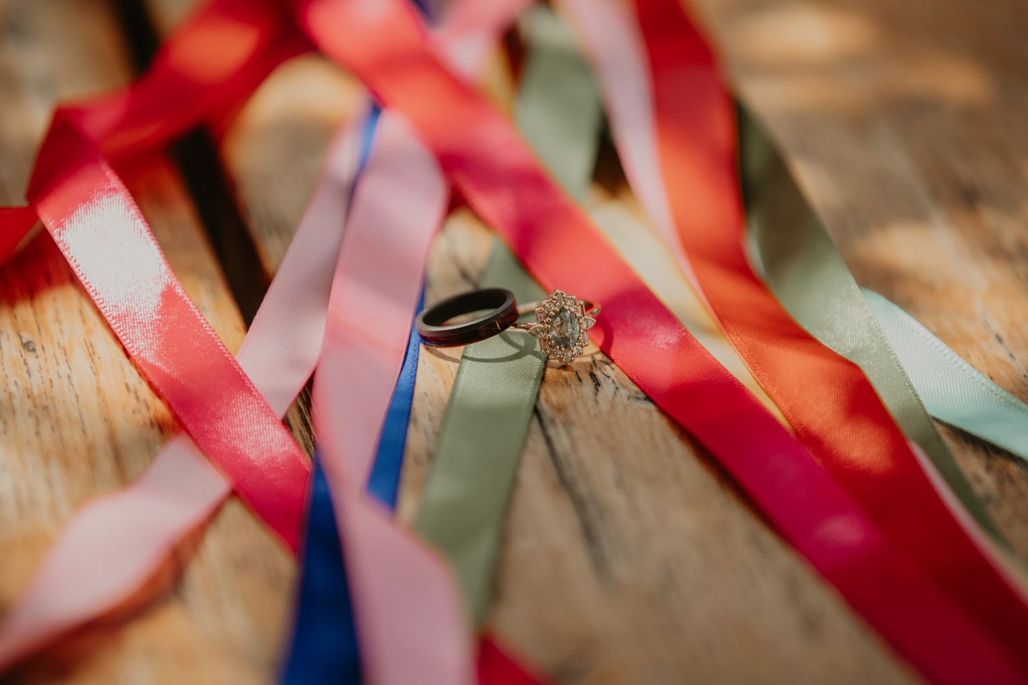 Colorful satin ribbons in pink, red, blue and mint green scattered on a rustic wooden surface.