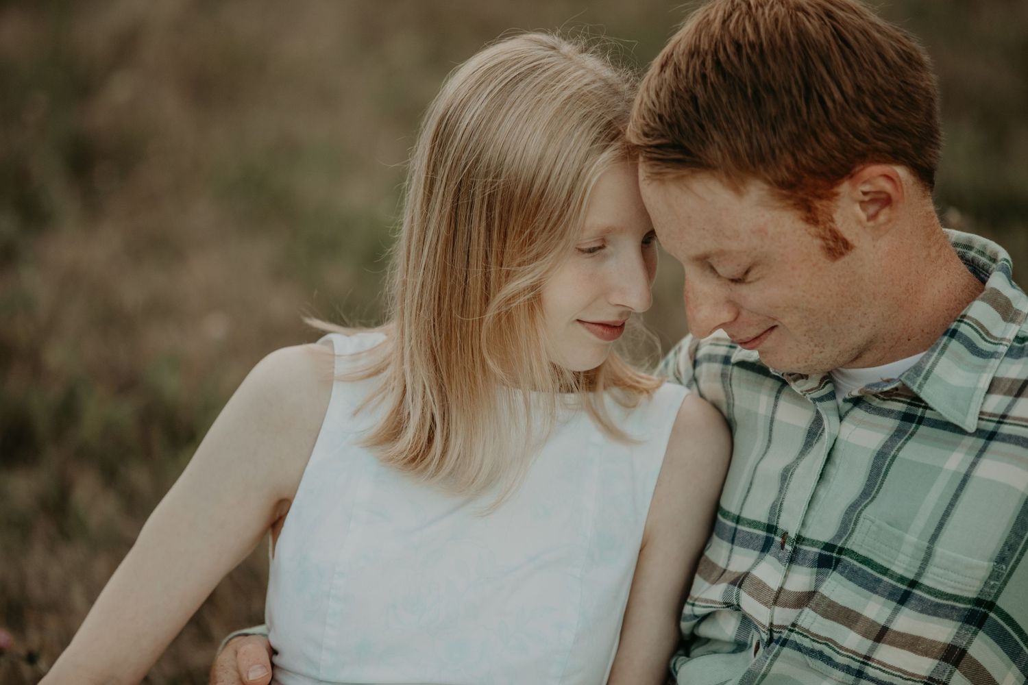 A loving couple embraces in a romantic outdoor photoshoot with moody earth-toned lighting and atmosphere.