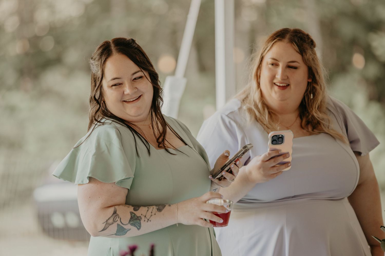 A wedding party laughs together while taking photos outdoors in a garden setting.