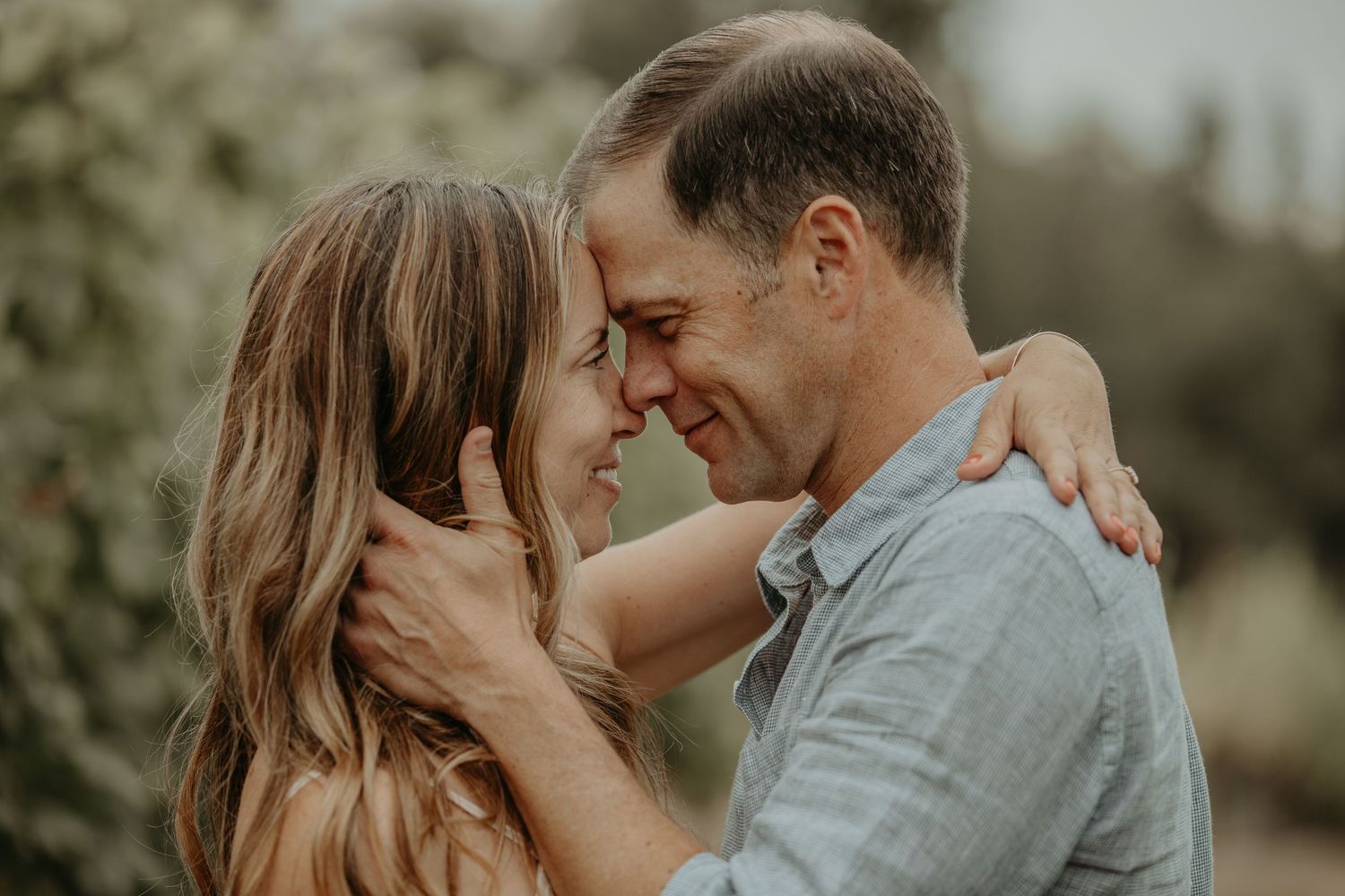 A romantic couple shares intimate moments in a natural outdoor setting during a golden hour photoshoot.