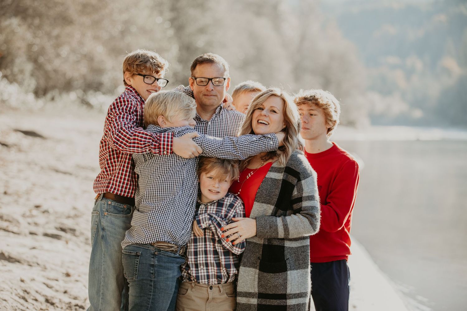 A happy family embraces together on a foggy beach during a winter photoshoot.