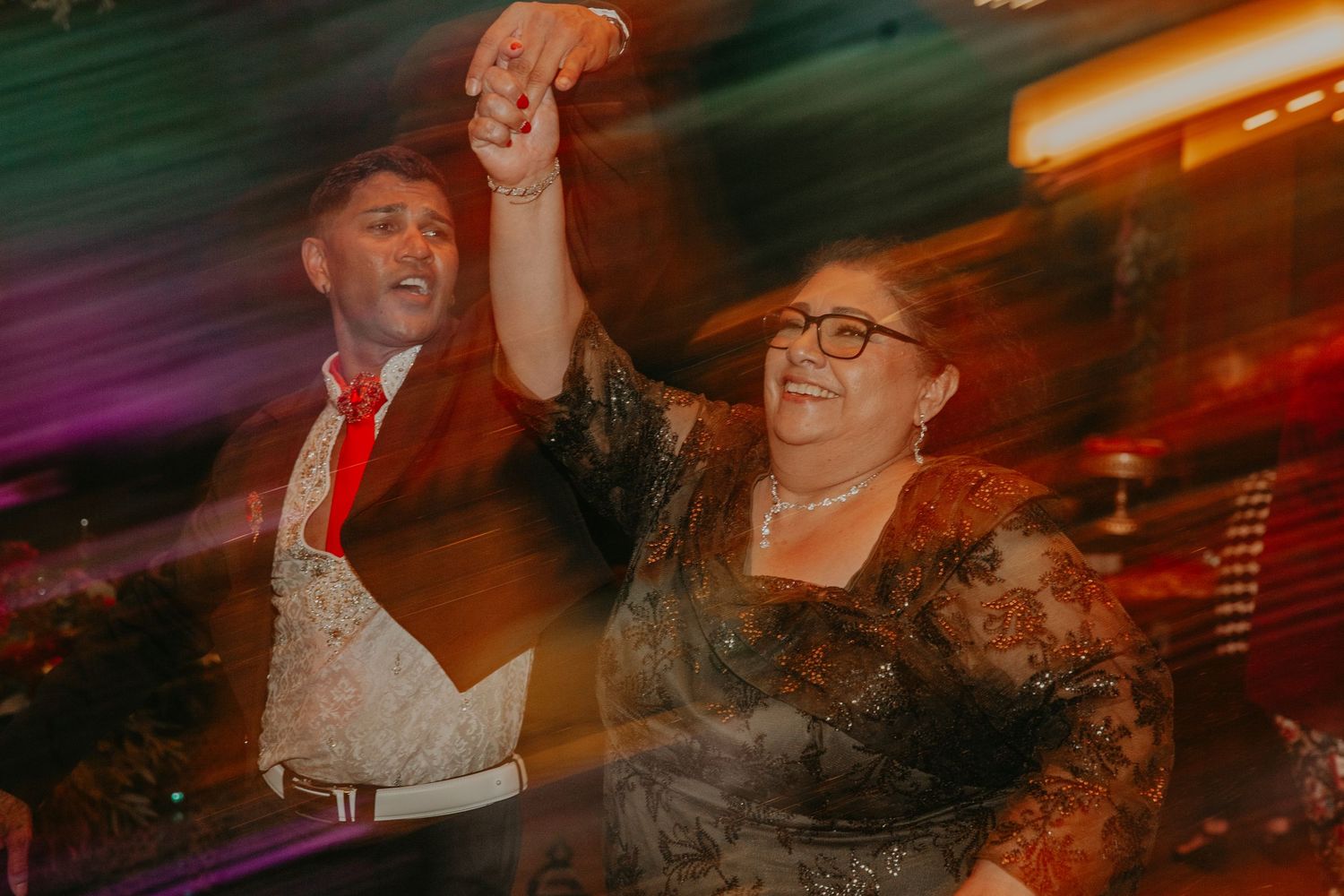 Colorful motion-blurred photos capture dancing and celebration at an evening reception event.