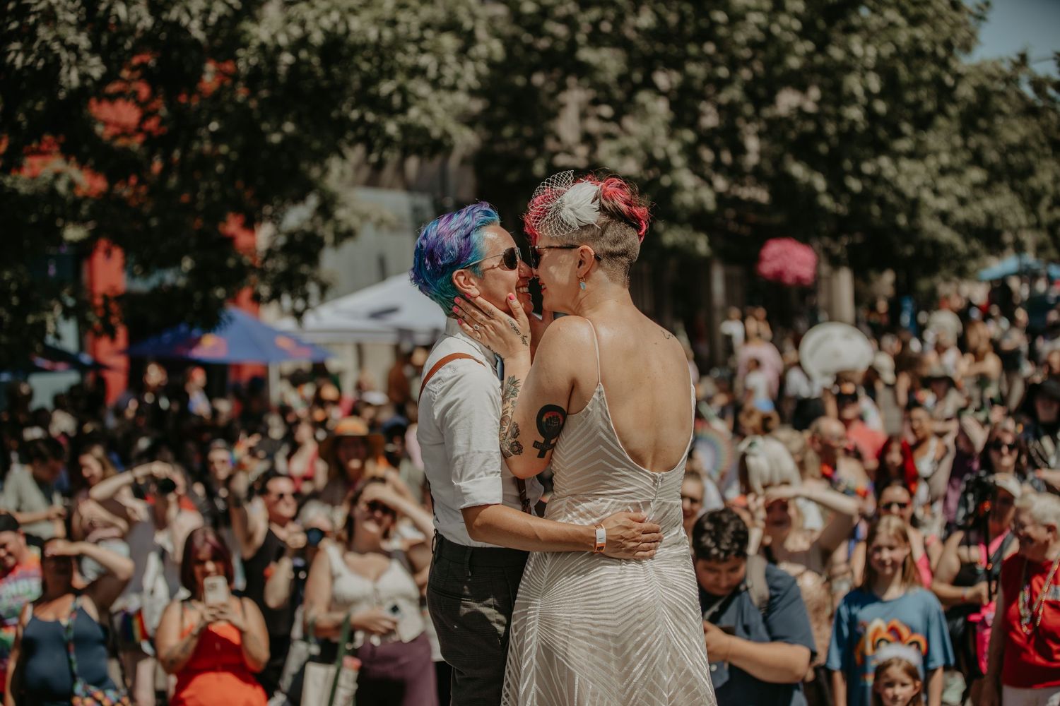 A festive outdoor gathering with people celebrating under trees and natural lighting.