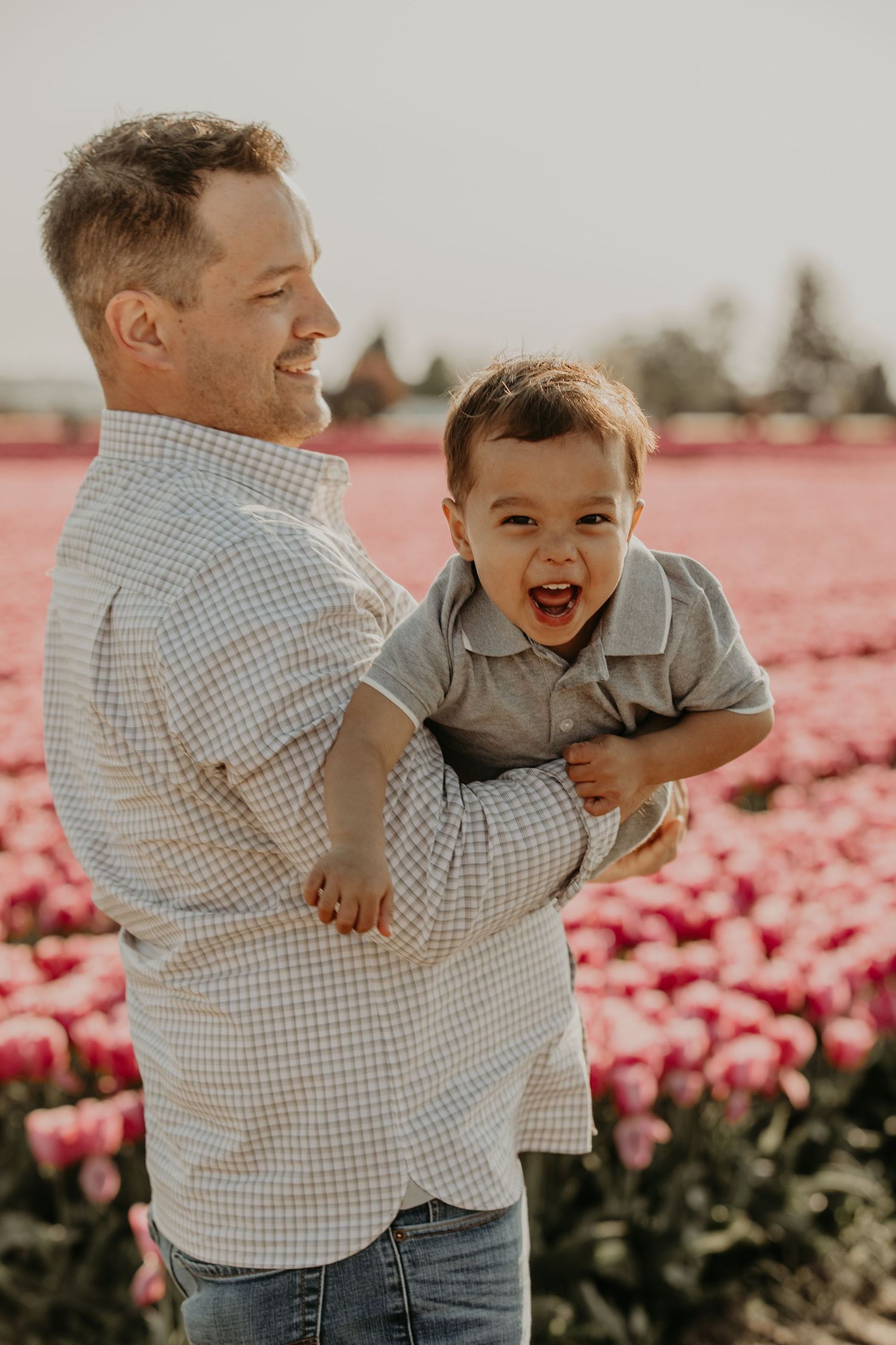 A joyful moment shared between parent and child in a blooming pink tulip field on a sunny day.