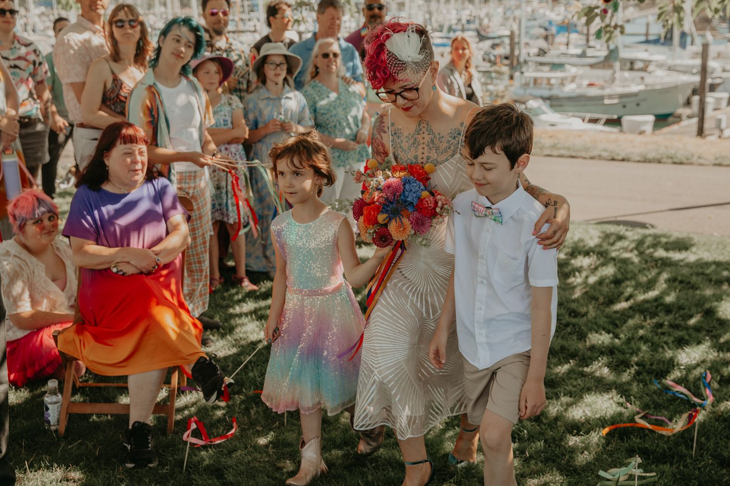 A group of wedding guests gathered outdoors in casual summer attire celebrating with sparklers.