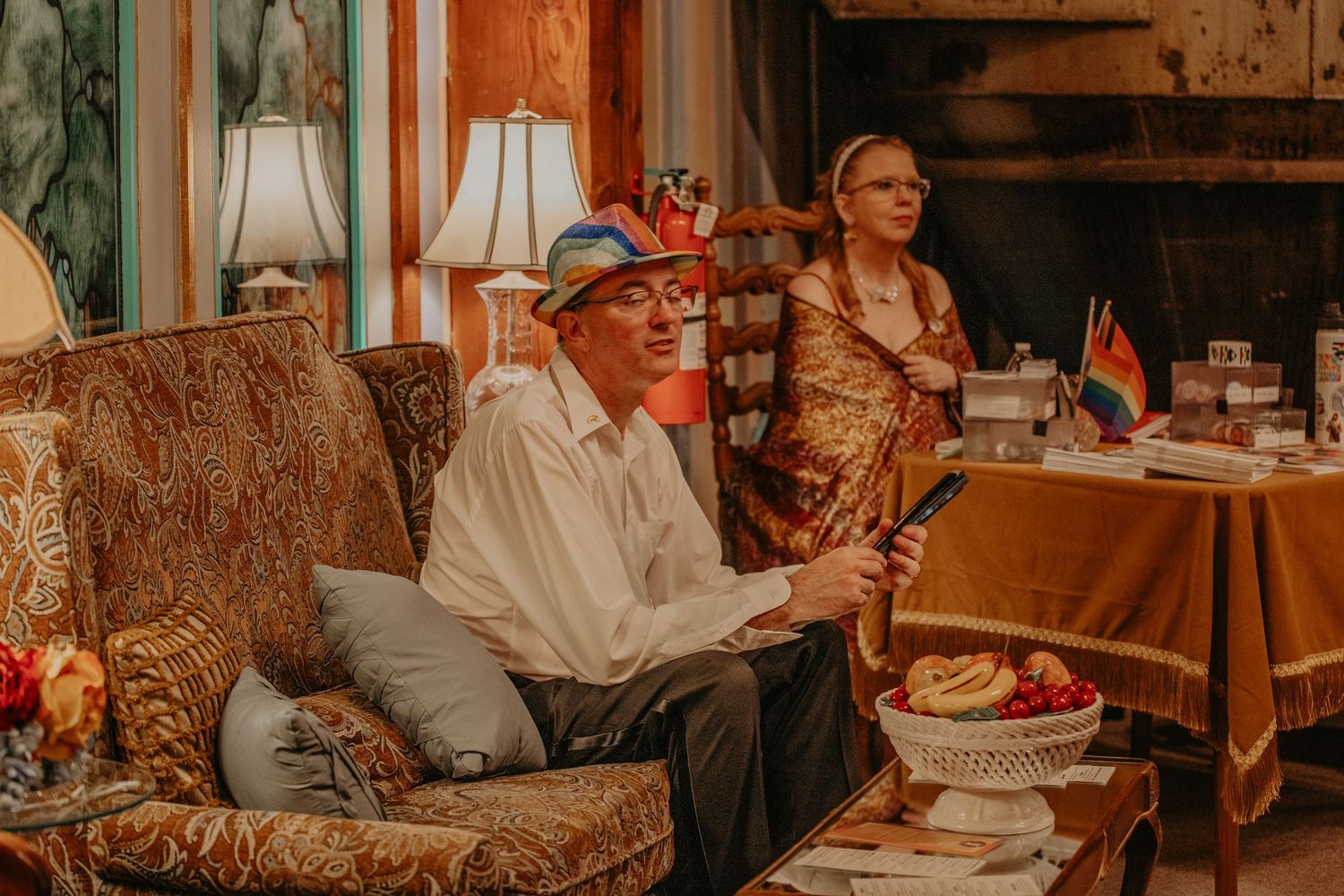 People wearing red and white festive attire sit in a cozy vintage living room at a holiday gathering.