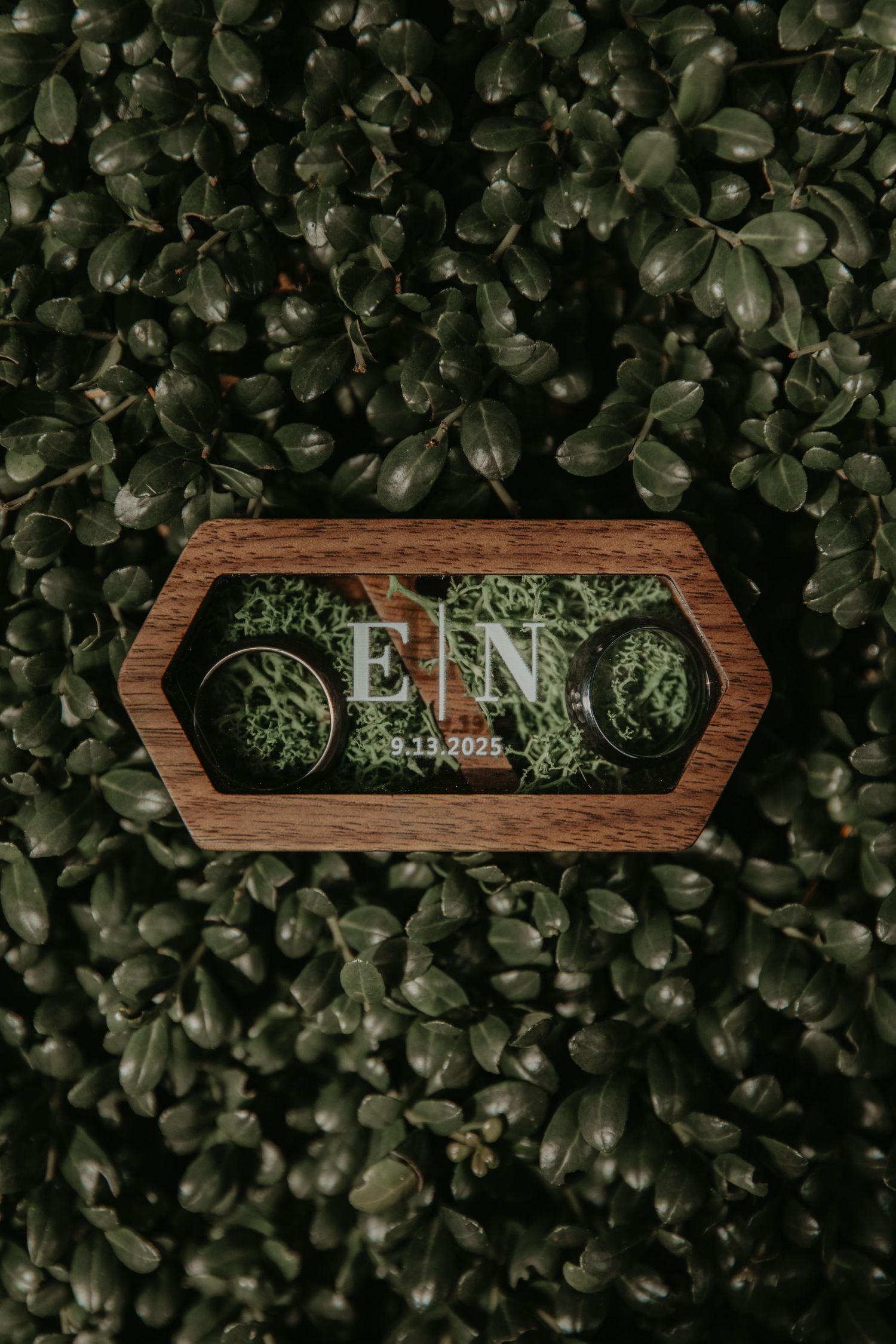 Wooden sign with elegant text mounted on a wall of lush green foliage.