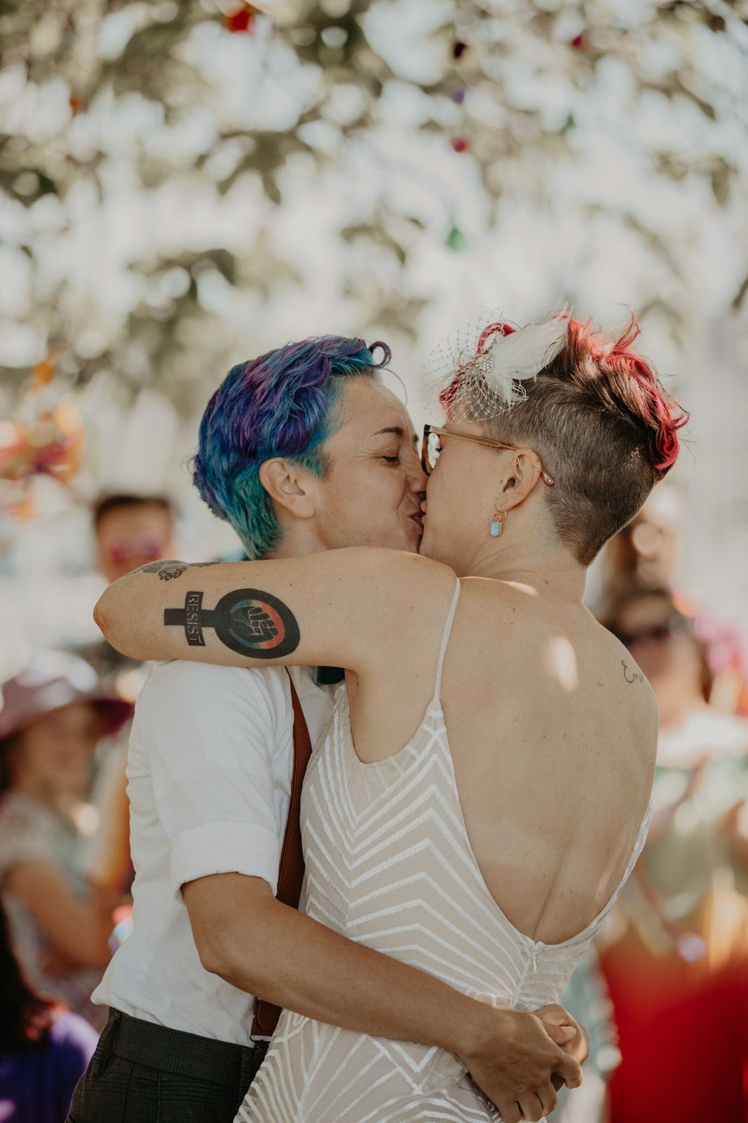 A couple sharing a kiss at their wedding celebration with colorful confetti in the background.