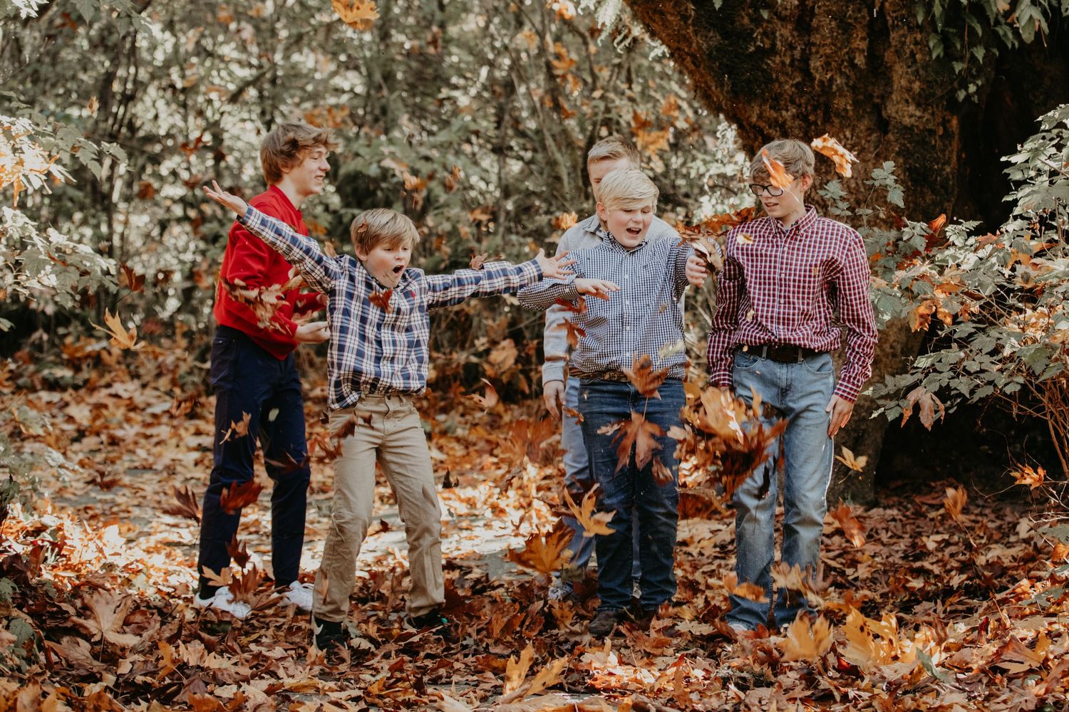 People walk together on a path covered in autumn leaves while holding hands on a fall day in nature.