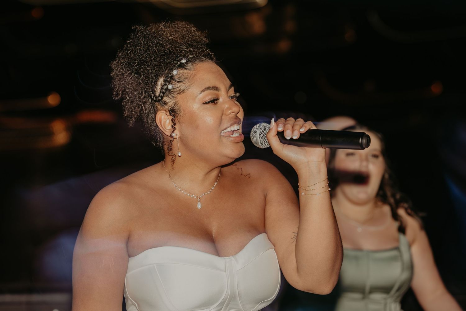 Wedding reception scene with someone singing into a microphone in dim lighting.