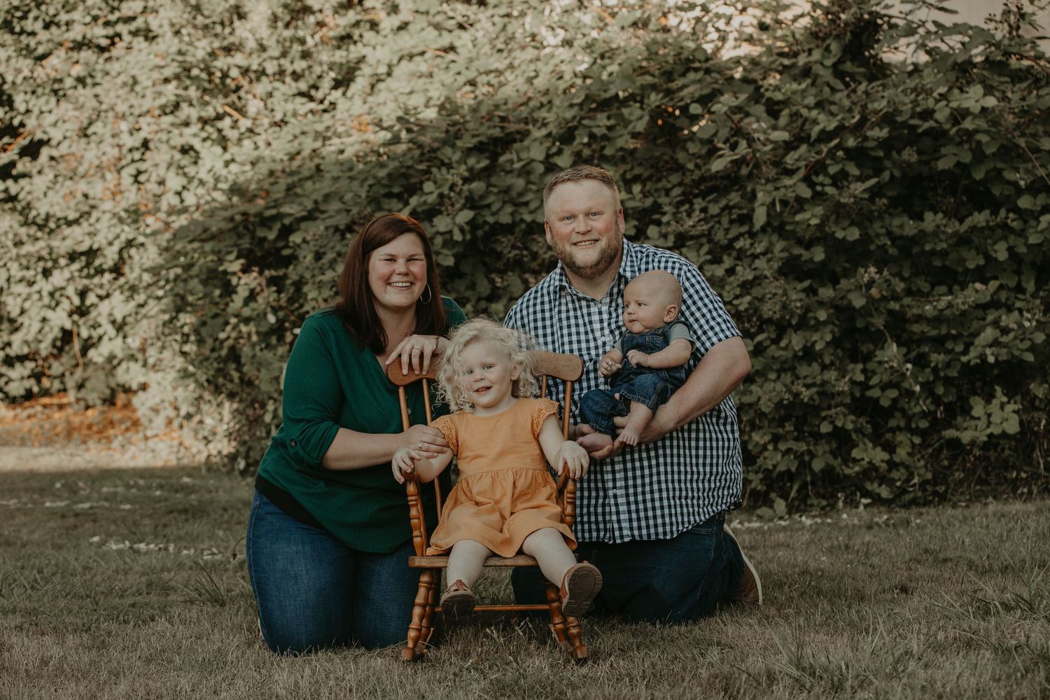 A sequence of outdoor family portraits taken on a lush grassy lawn with stone wall backdrop.