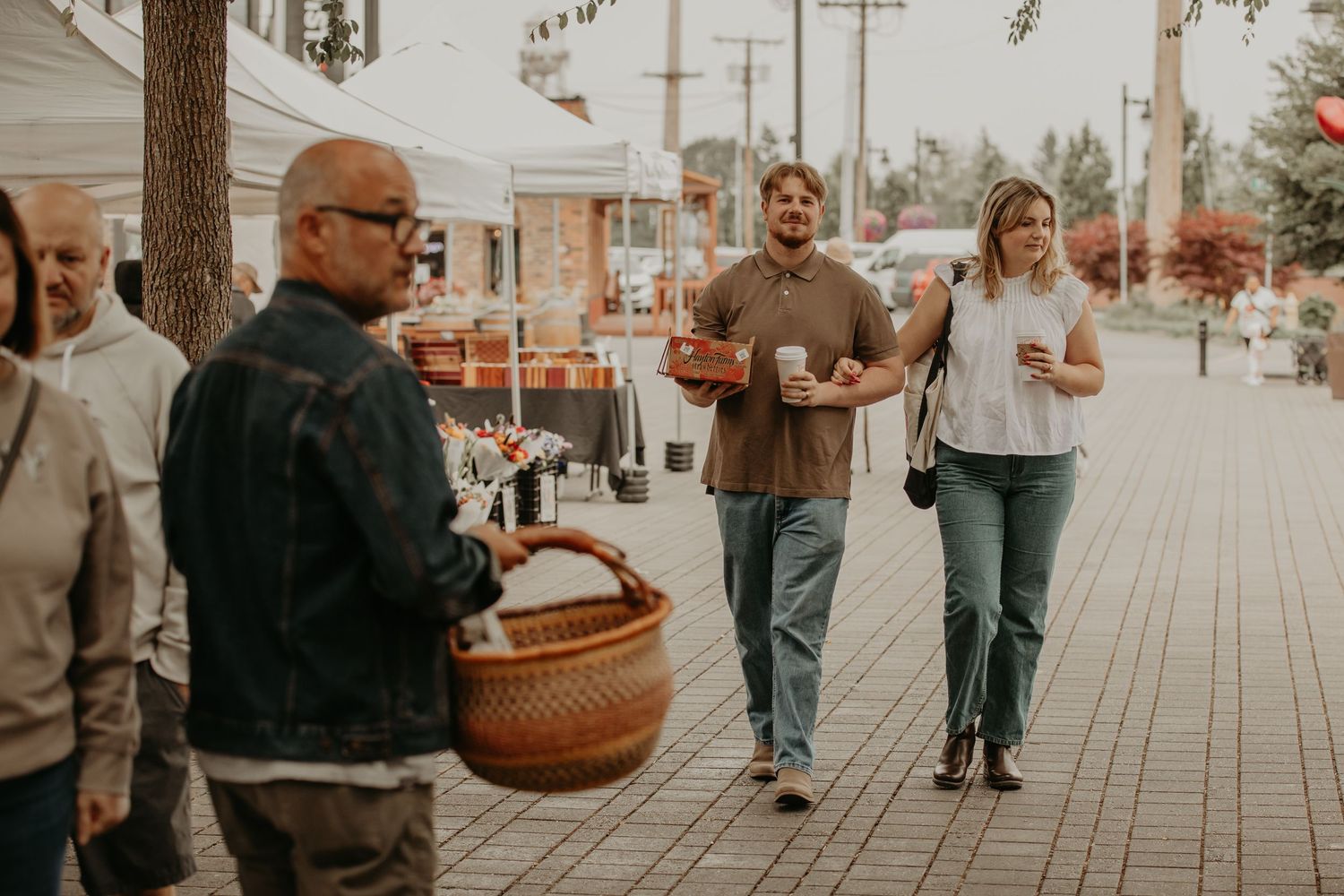 A group walks together on a sidewalk while one member carries a woven basket on a sunny day.
