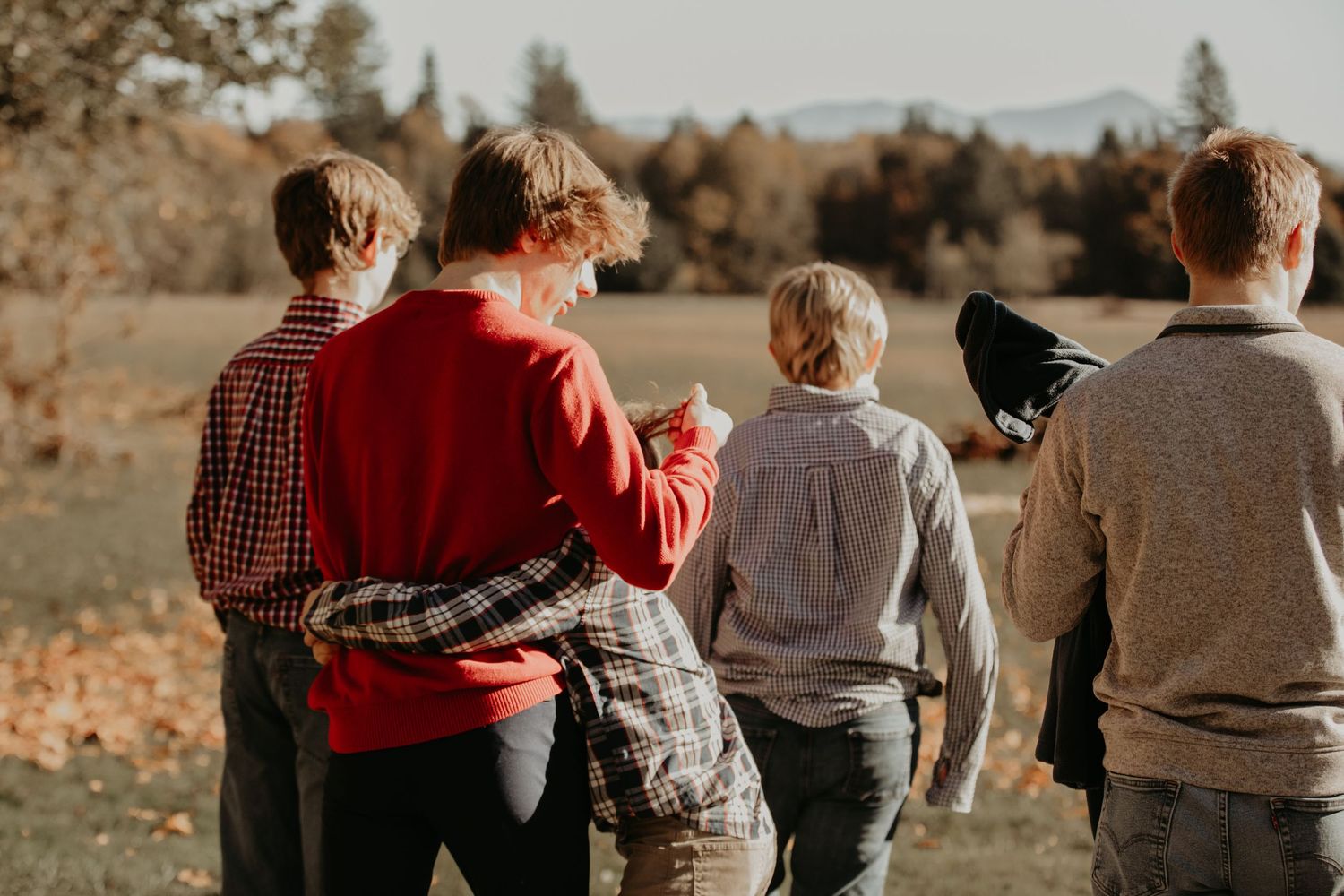 A group walks together outdoors in autumn with fall foliage and sunlight in a scenic natural setting.