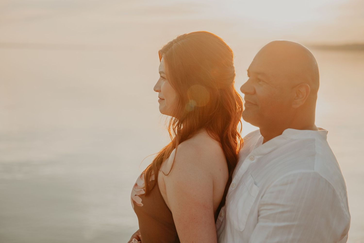 A couple enjoys a romantic moment together during golden hour against a misty sunset backdrop.