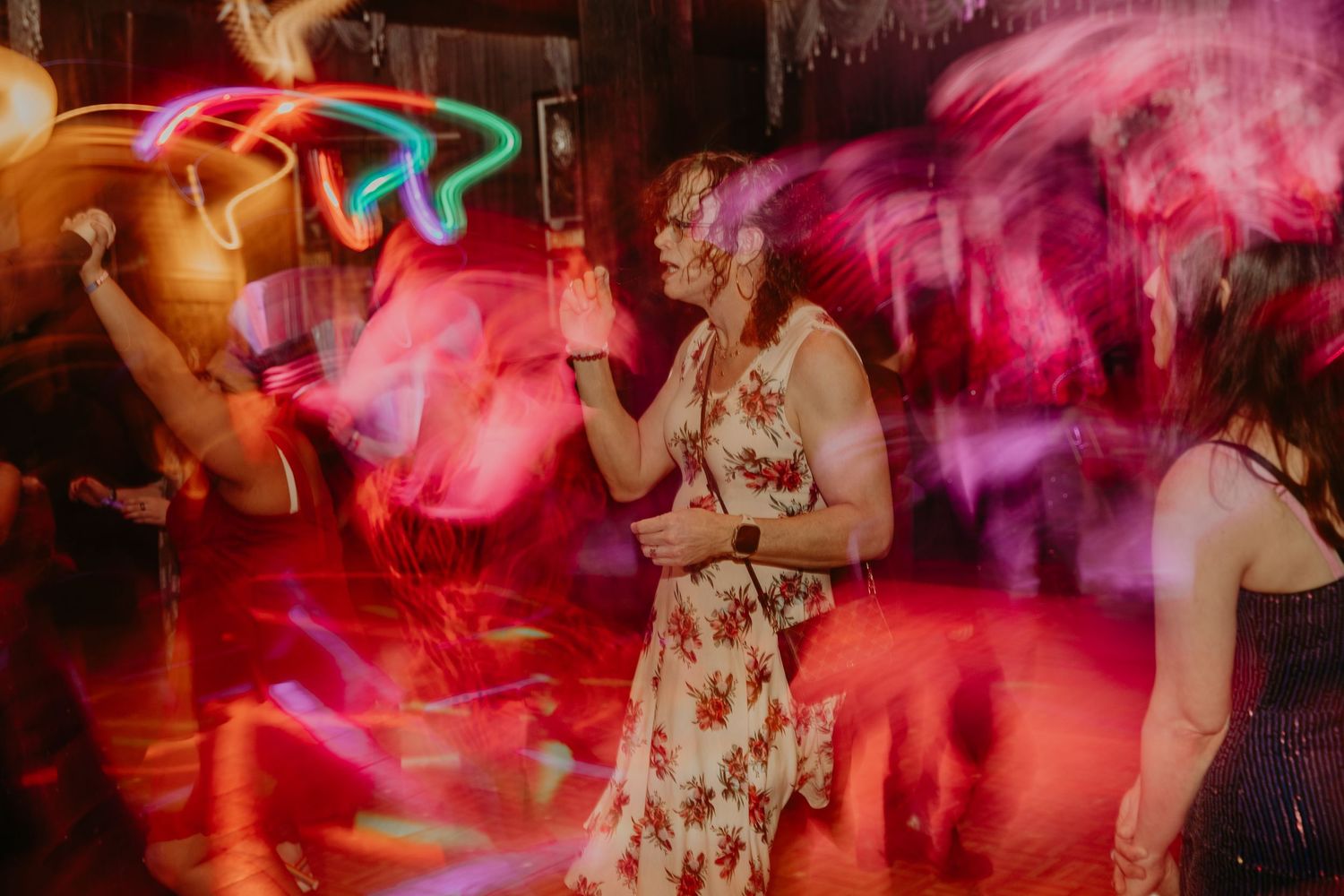 People dancing at a nightclub with vibrant red lighting and motion blur effects creating a dynamic party atmosphere.