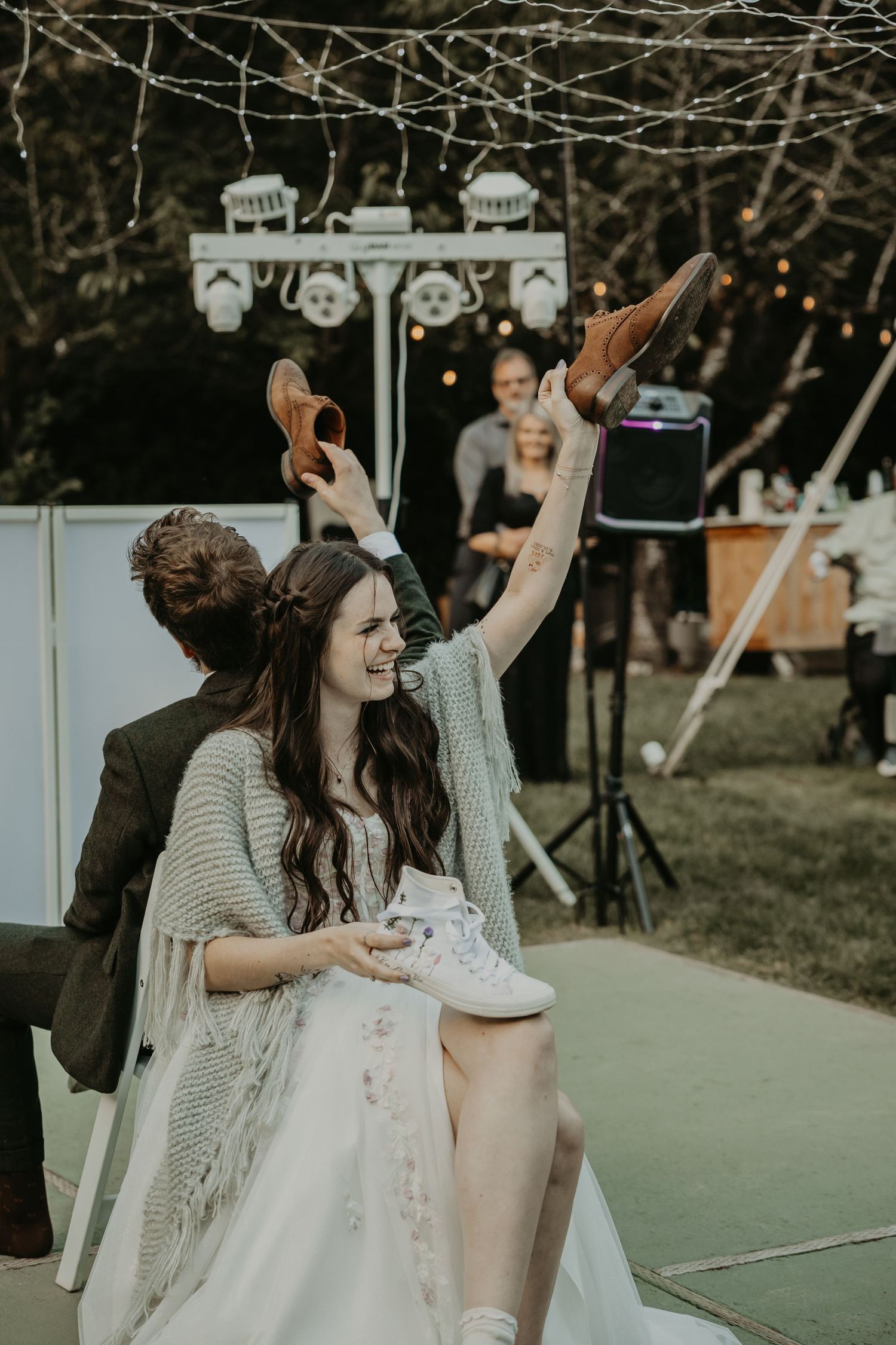 A joyful wedding reception dance party with people celebrating outdoors on a dance floor during sunset.