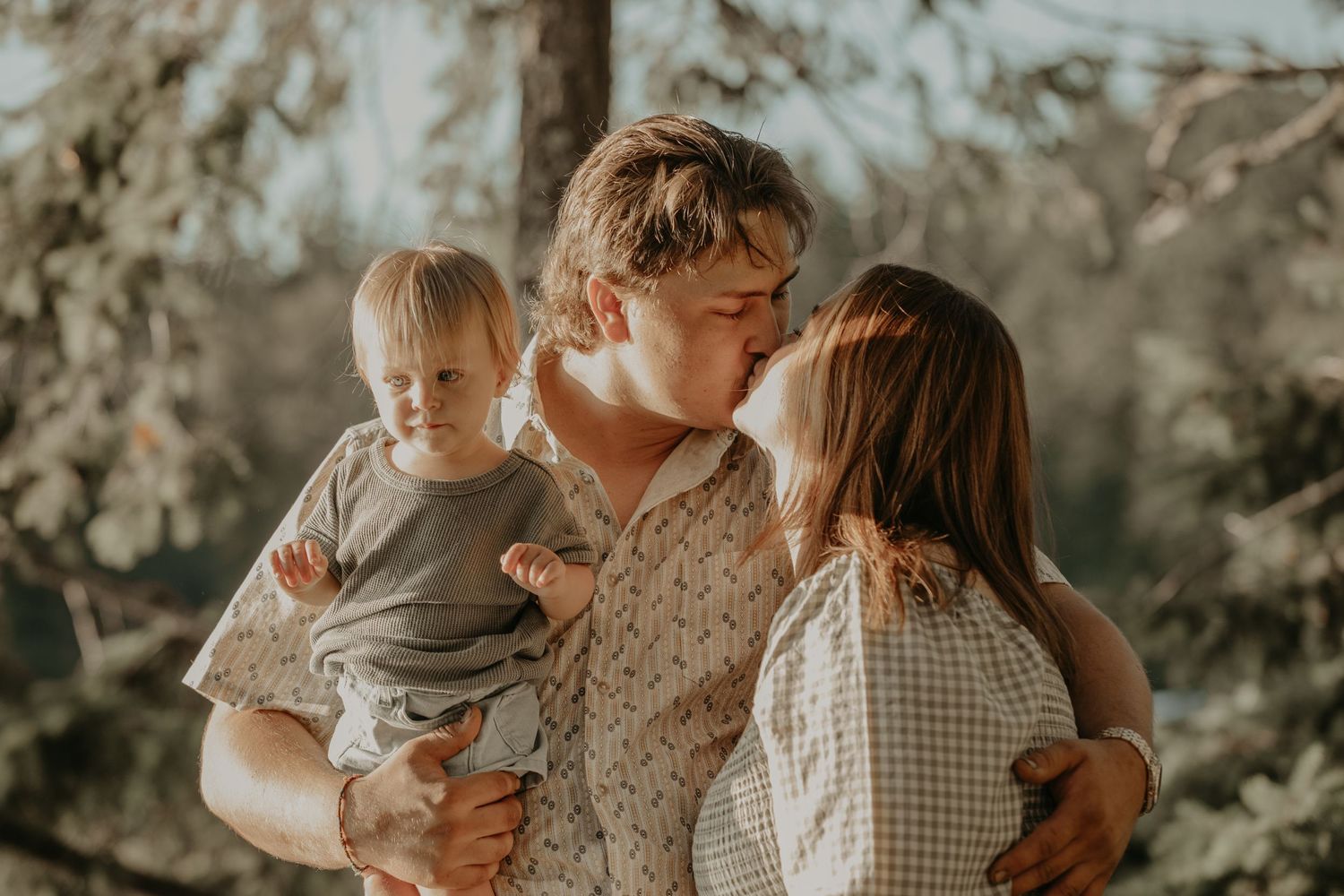 Warm toned natural light portraits of family embracing outdoors in a rustic setting.