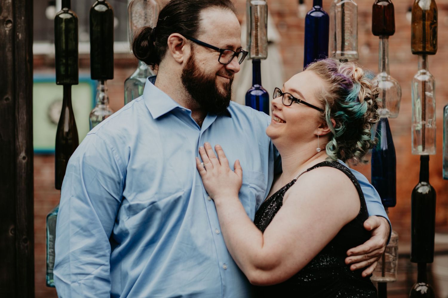 A joyful couple share a loving moment together against a backdrop of hanging vintage wind chimes.