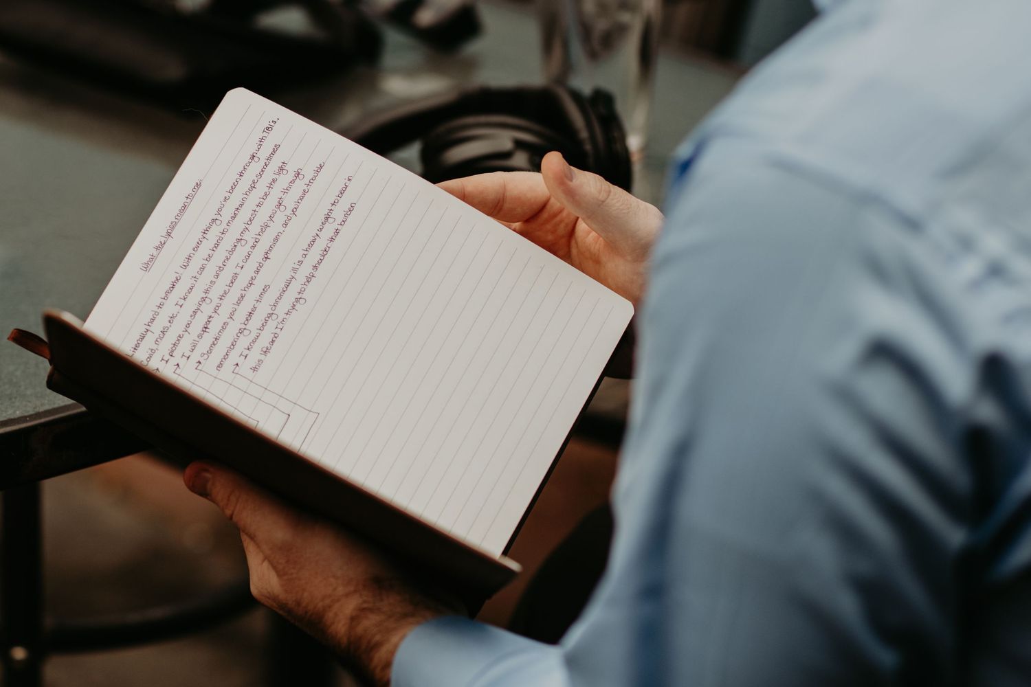 A close up view of hands holding a small notebook with lined paper in a professional setting.
