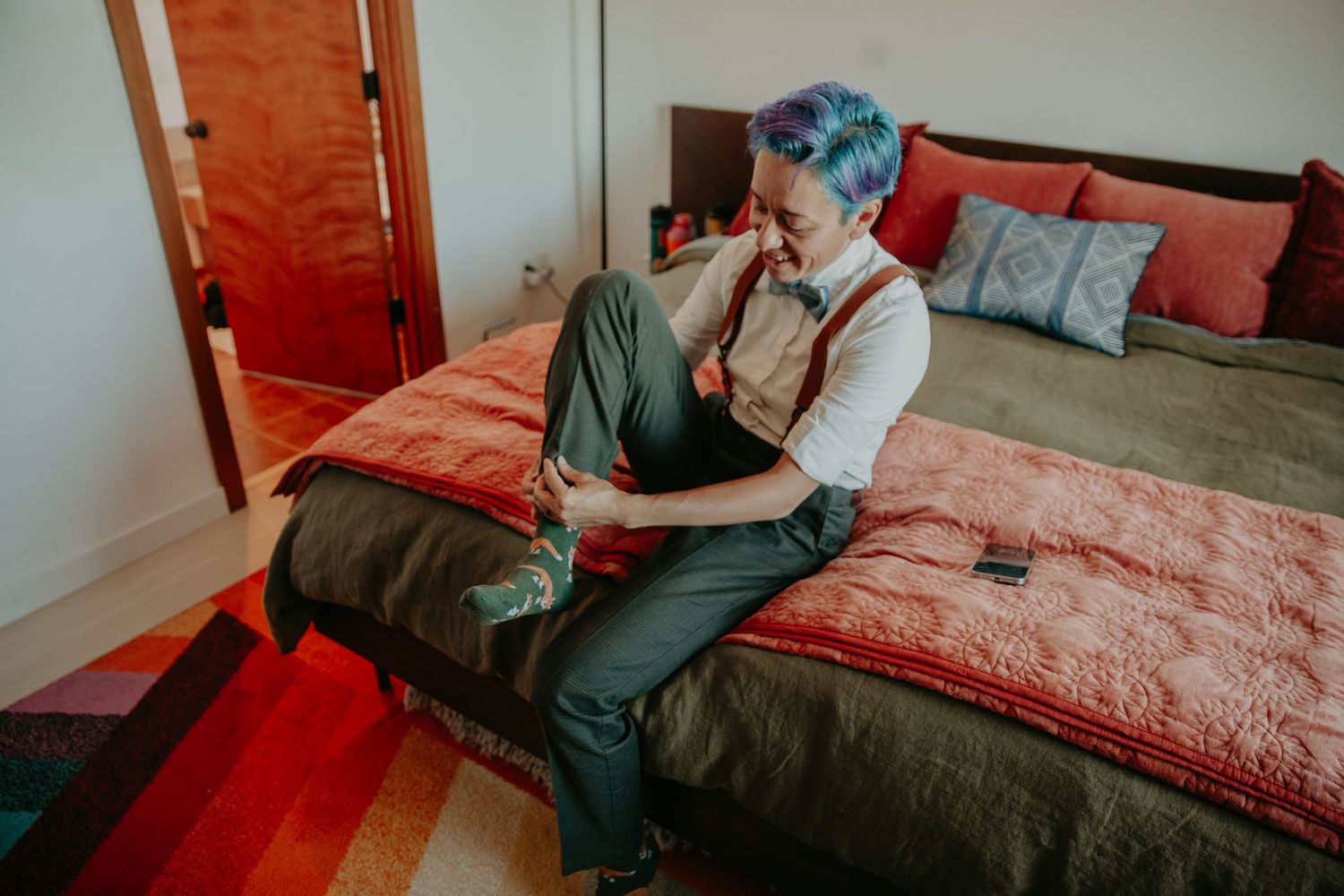 Intimate couple shares tender moments on a red and white bed in a cozy bedroom setting.