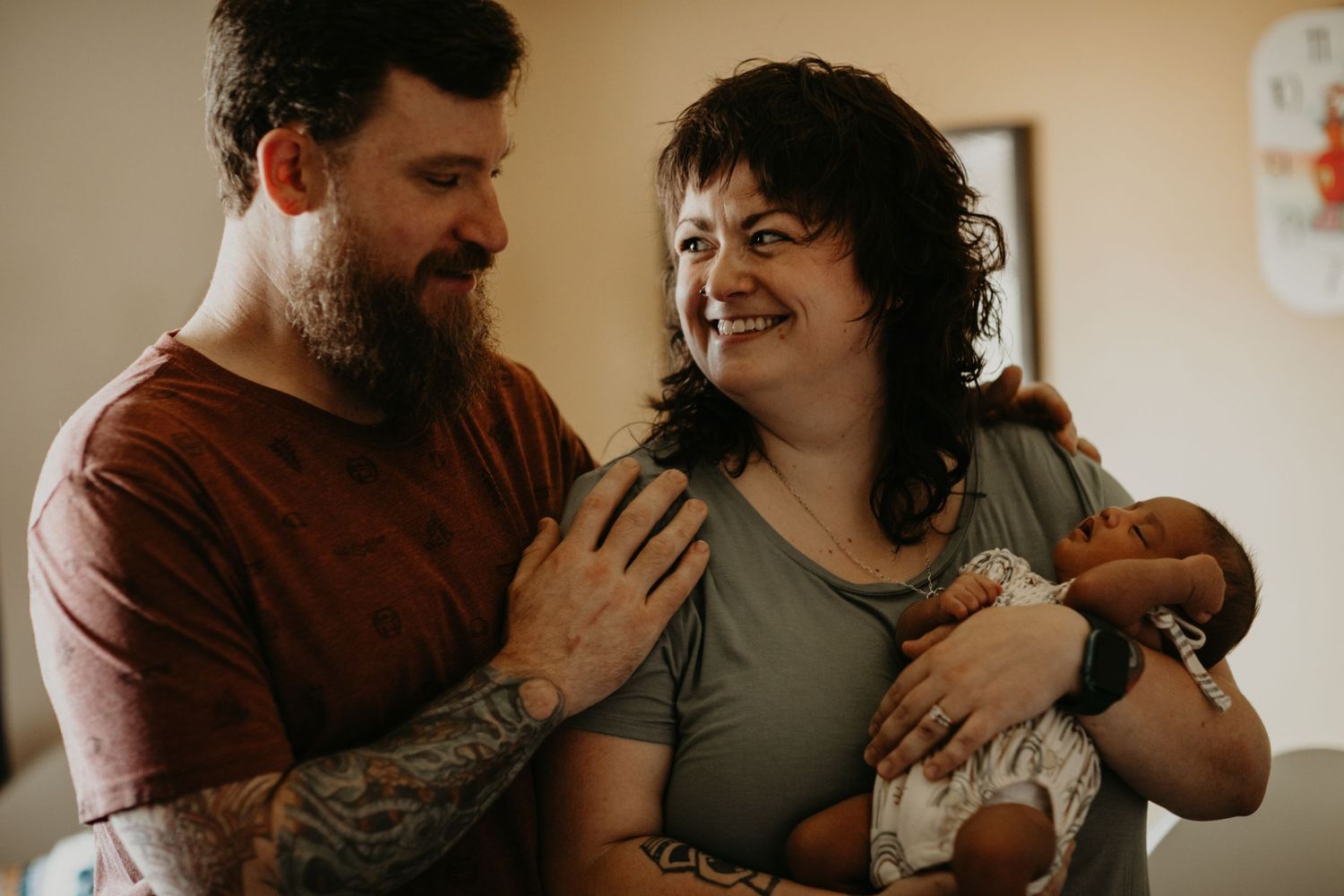 A couple shares an intimate moment together while laughing and embracing in warm indoor lighting.