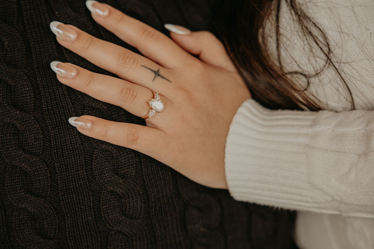 Close-up shots of hands wearing a silver engagement ring with a white knit sweater sleeve.