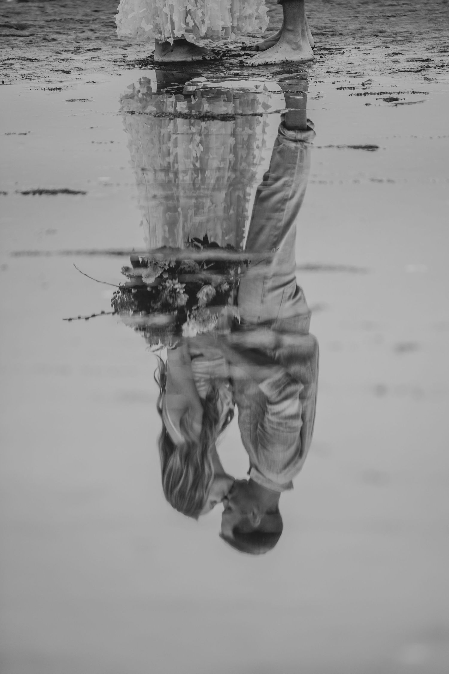 Artistic black and white reflection of legs in still water creating a mirror-like symmetrical effect.