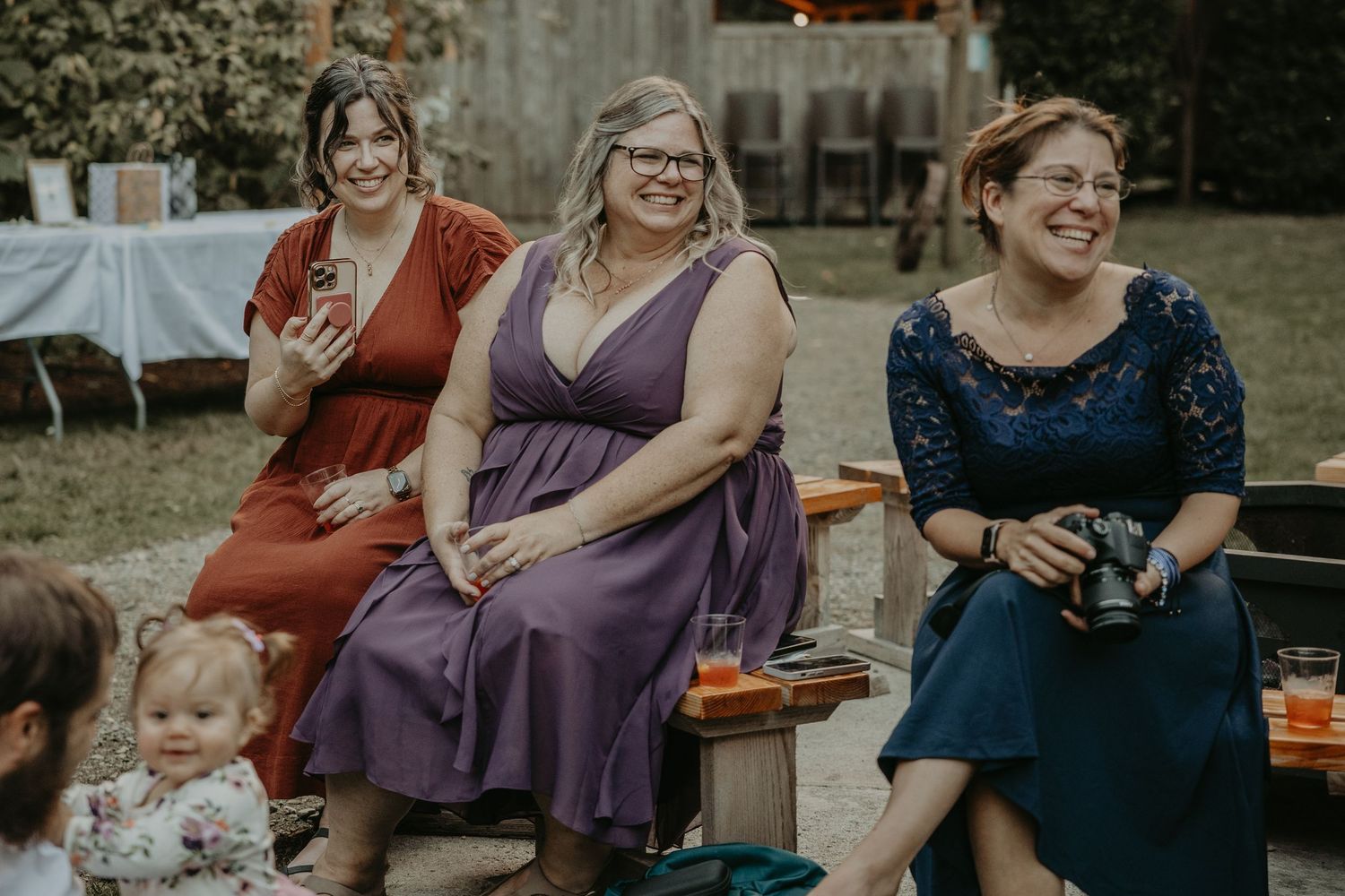 People enjoying a casual outdoor gathering with laughter and conversation in a backyard setting.