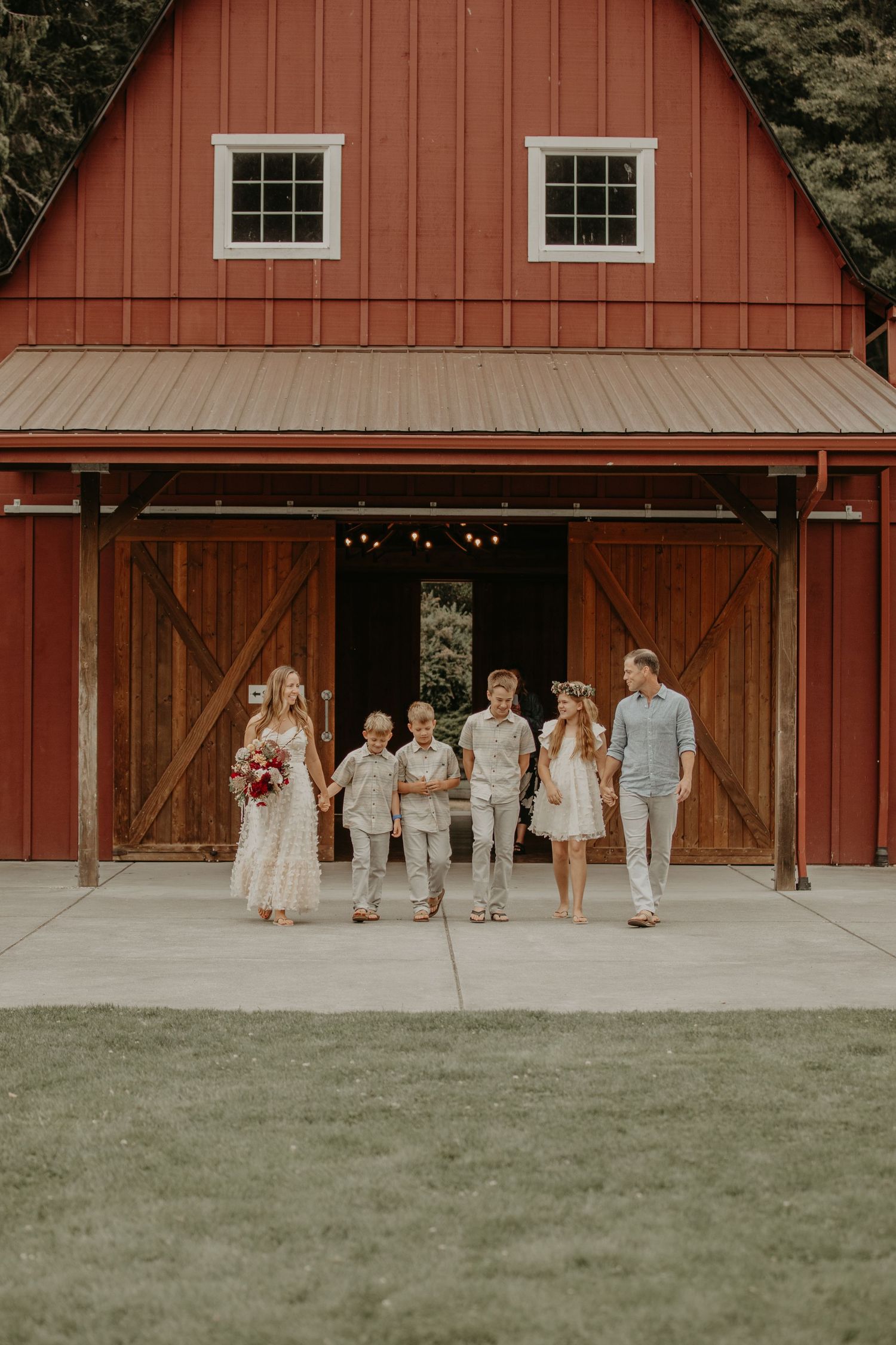 A rustic red barn wedding venue with people gathered outside on a grassy lawn.