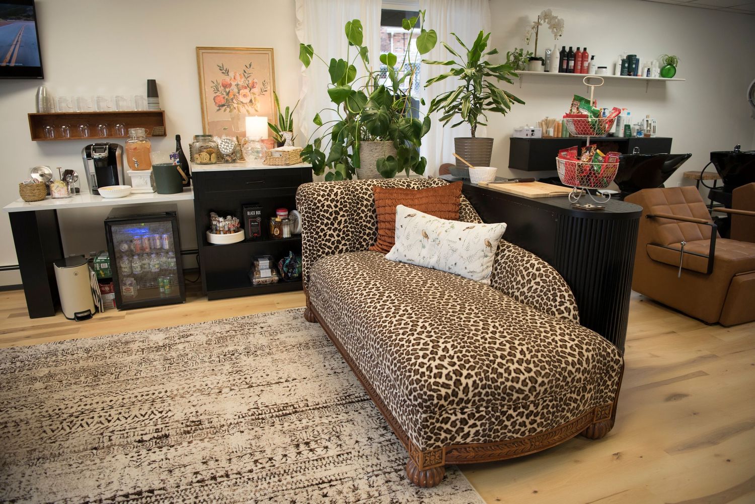 A cozy lounge area with animal print chaise, plants, and wooden furniture in a modern interior setting.