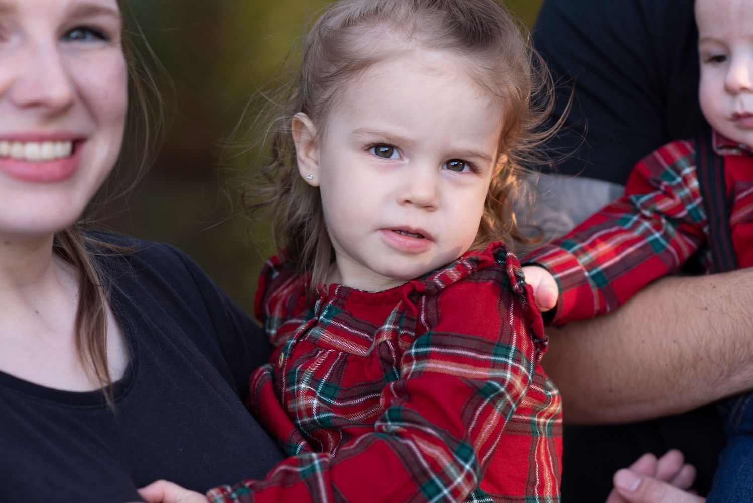 Close-up portrait shots showing matching red plaid outfits during an outdoor autumn photo session.