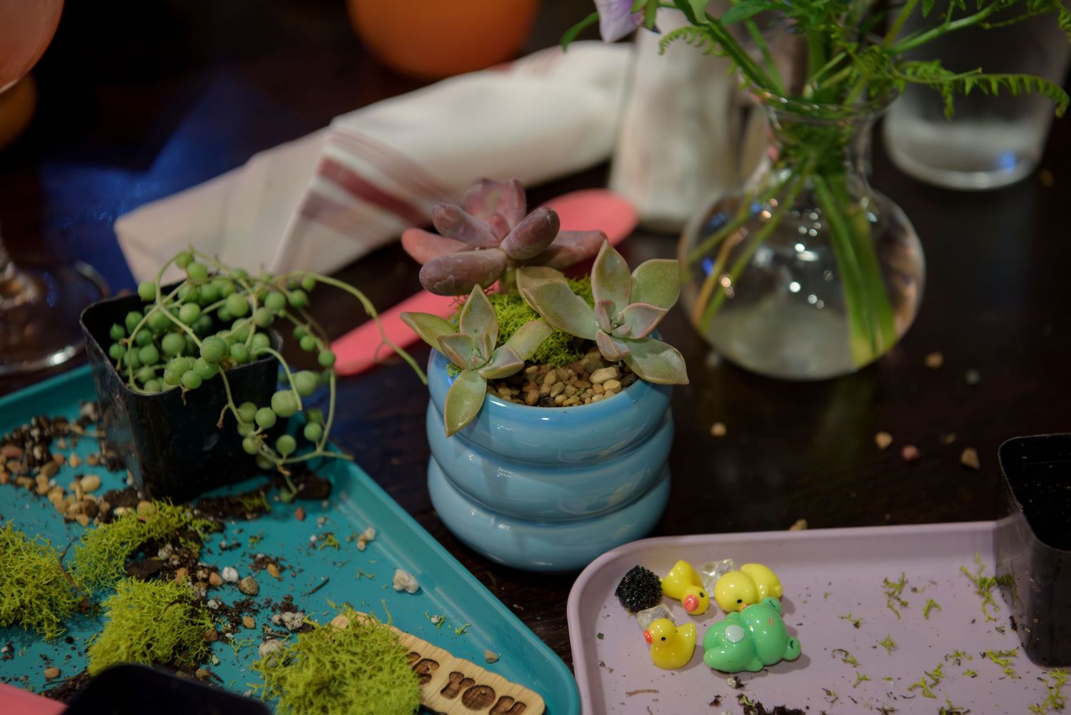 Fresh herbs and greens being chopped on a wooden cutting board with kitchen tools and glass containers nearby.